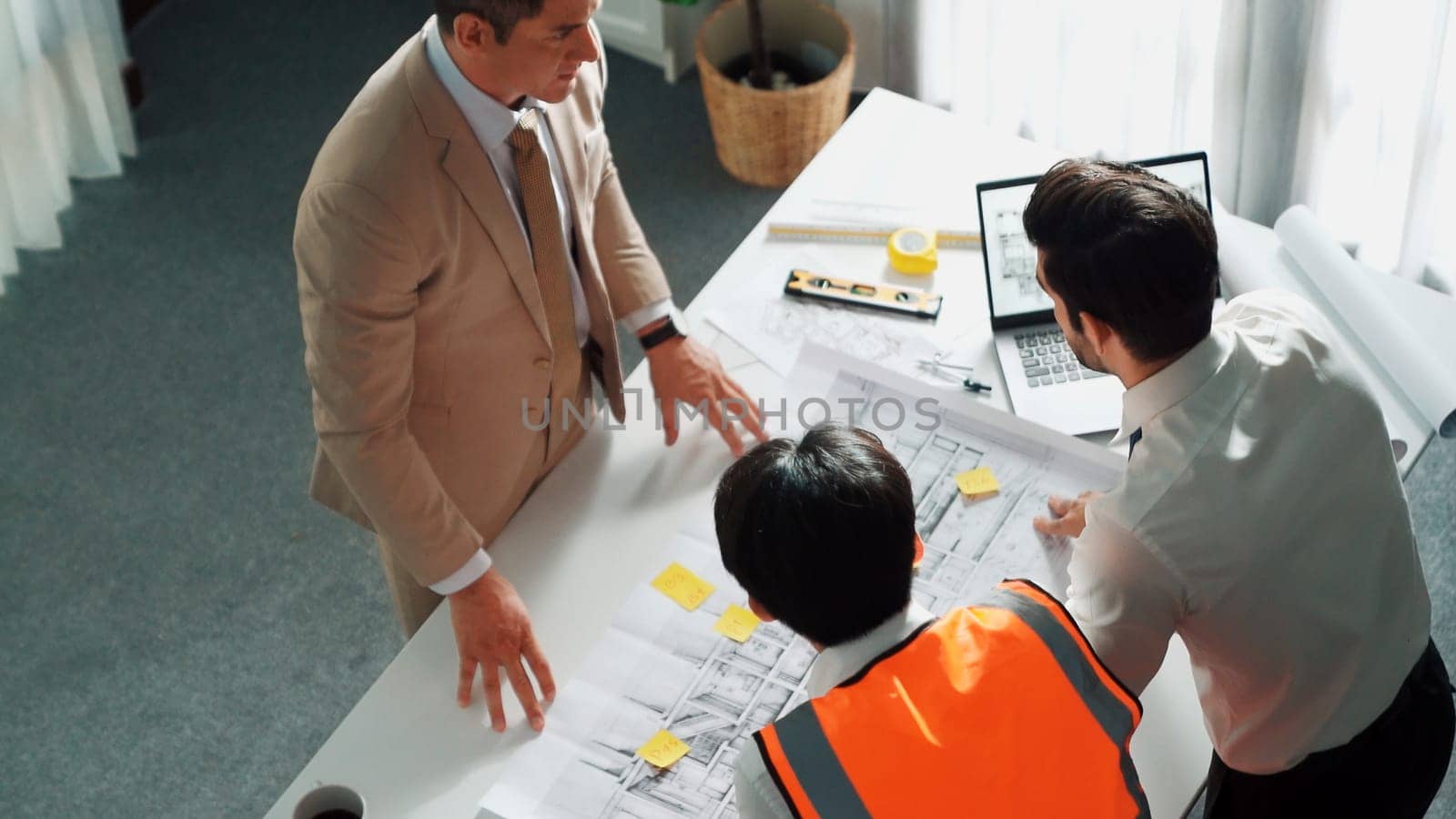 Top view of professional architect engineer team inspect house model while manager holding blueprint and asking about building construction. Group of diverse engineer working together. Alimentation.