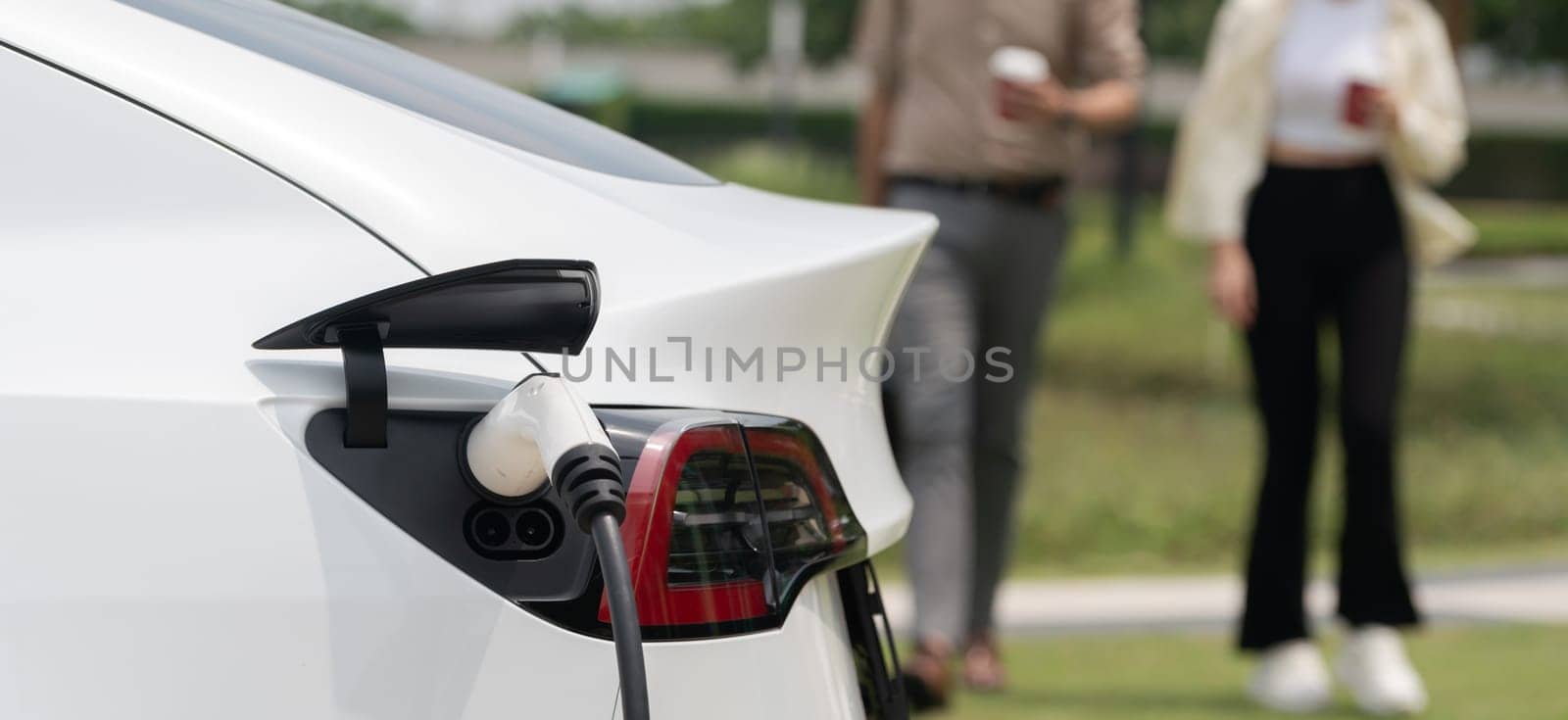 Young couple put EV charger to recharge electric car battery. Expedient by biancoblue