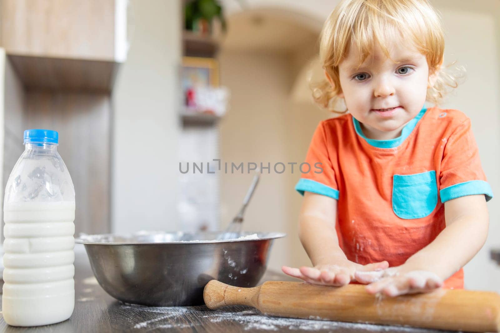 Little child baking in the kitchen. Toddler's hands rolling dough with wooden pin. Family and childhood concept with copy space. Design for banner, poster