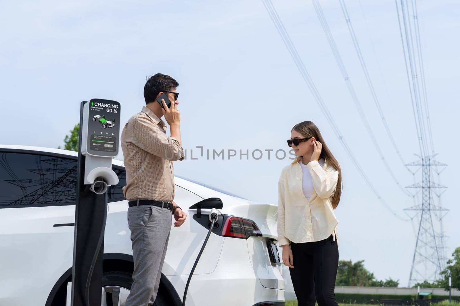 Couple recharge EV car battery at charging station. Expedient by biancoblue