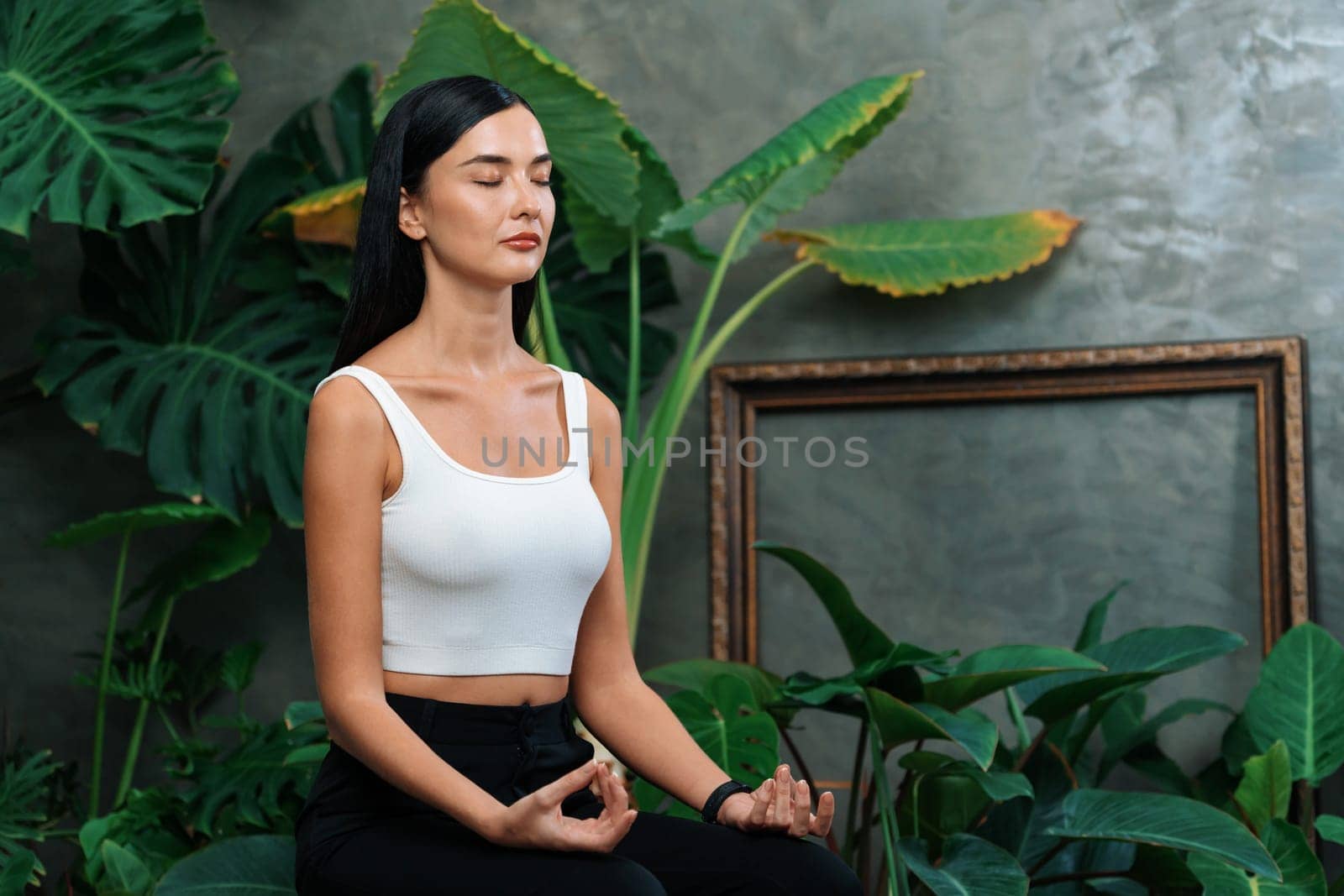 Young woman doing morning yoga and meditation in natural garden with plant leaf, enjoying the solitude and practicing meditative poses. Mindfulness activity and healthy mind lifestyle. Blithe