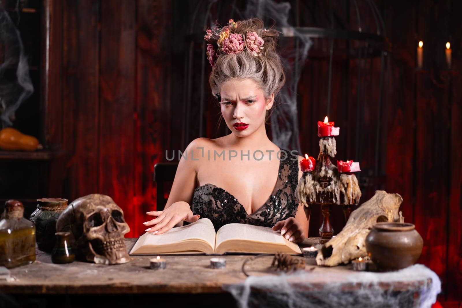 Portrait fortune teller woman reading future on magical book. Magic and divination. Young beautiful enchanted female witch sitting on the table waiting your desire. Scary Halloween atmosphere
