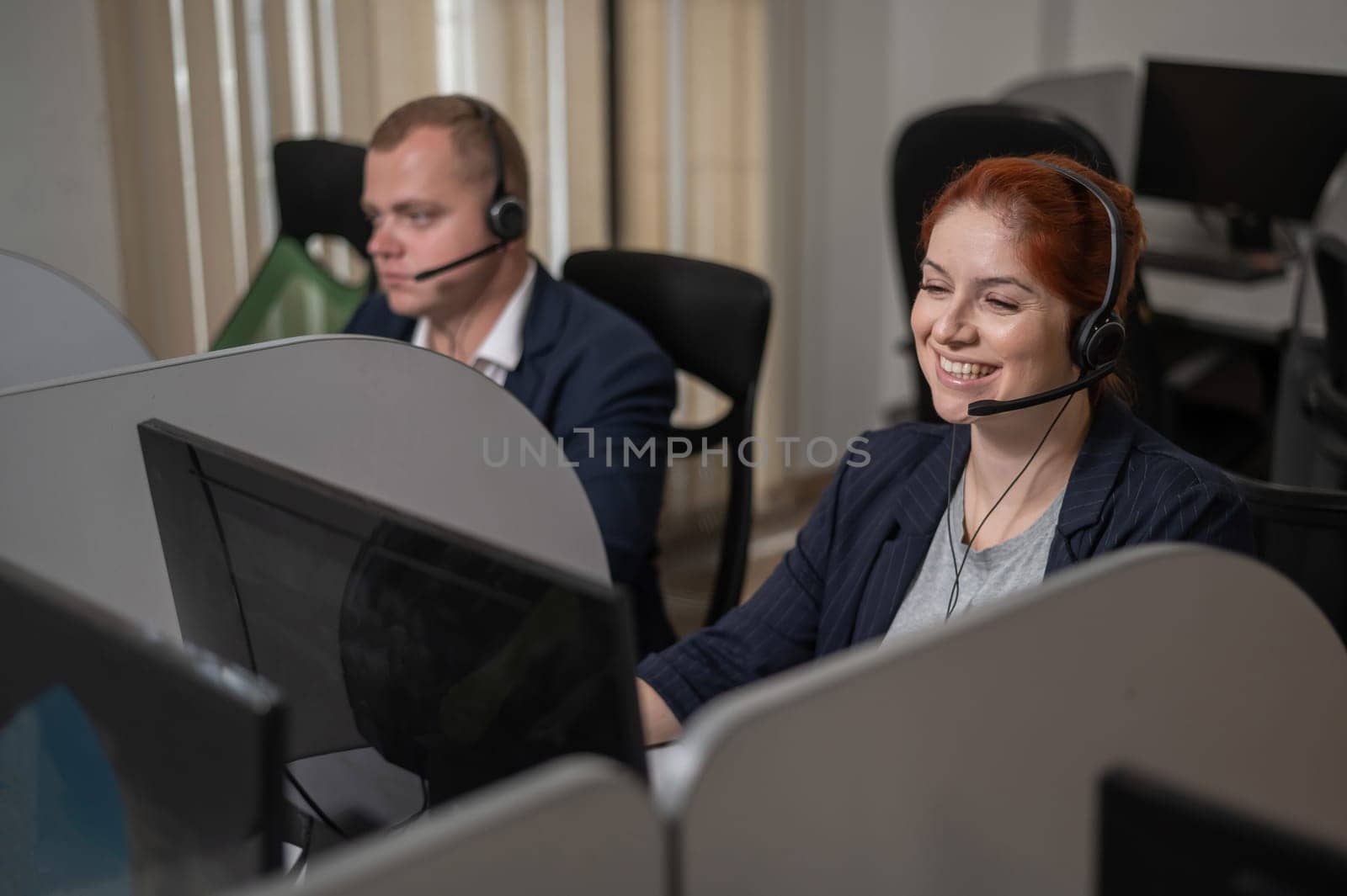 Two friendly call center employees answer customers by phone. Man and woman woman talking on a headset in the office. by mrwed54