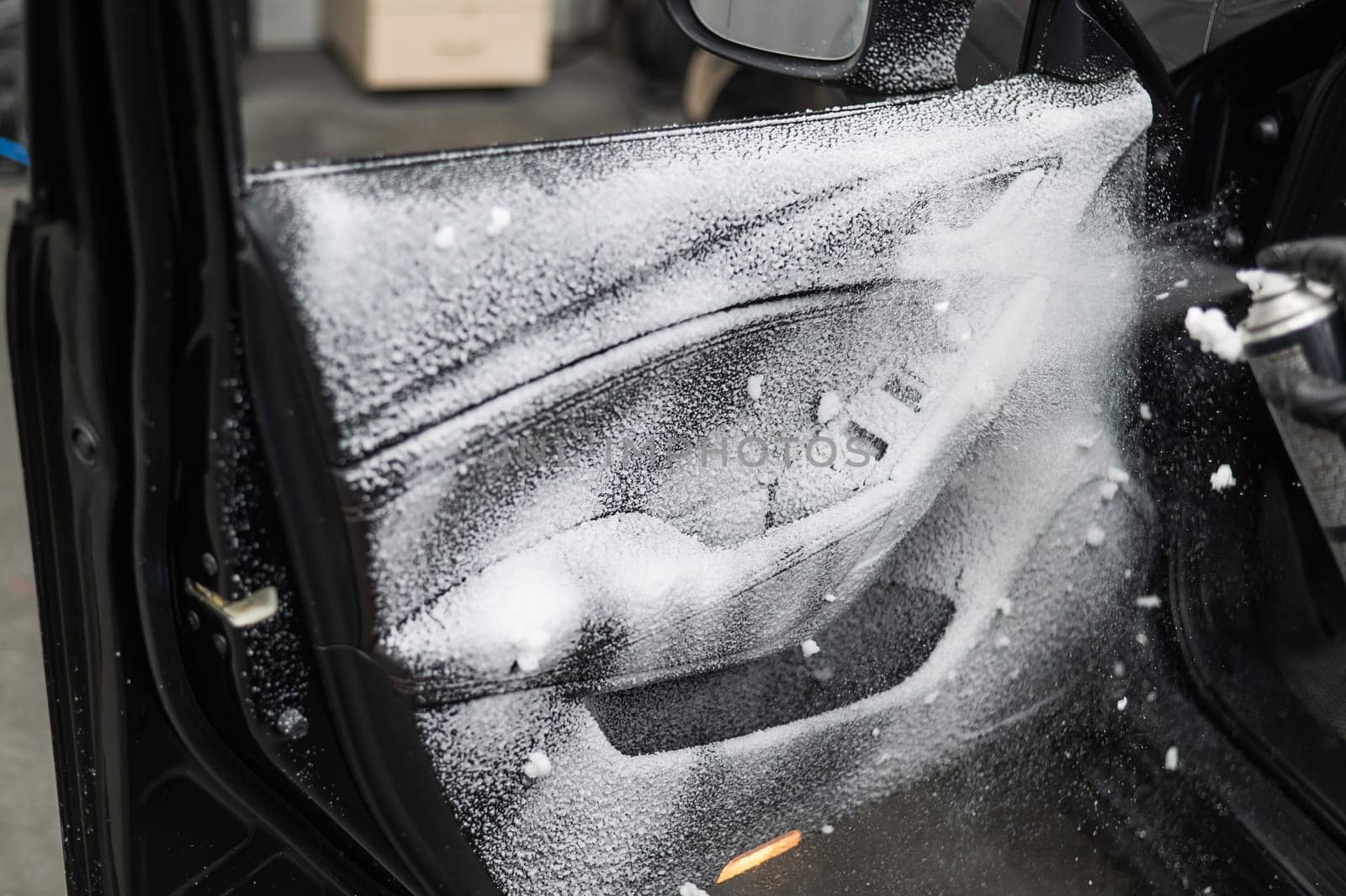A man sprays cleaning foam on the interior of a car. by mrwed54