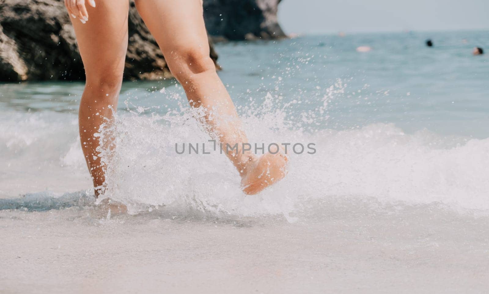 Sea beach travel - woman walking on sand beach leaving footprints in the white sand. Female legs walking along the seaside barefoot, close-up of the tanned legs of a girl coming out of the water