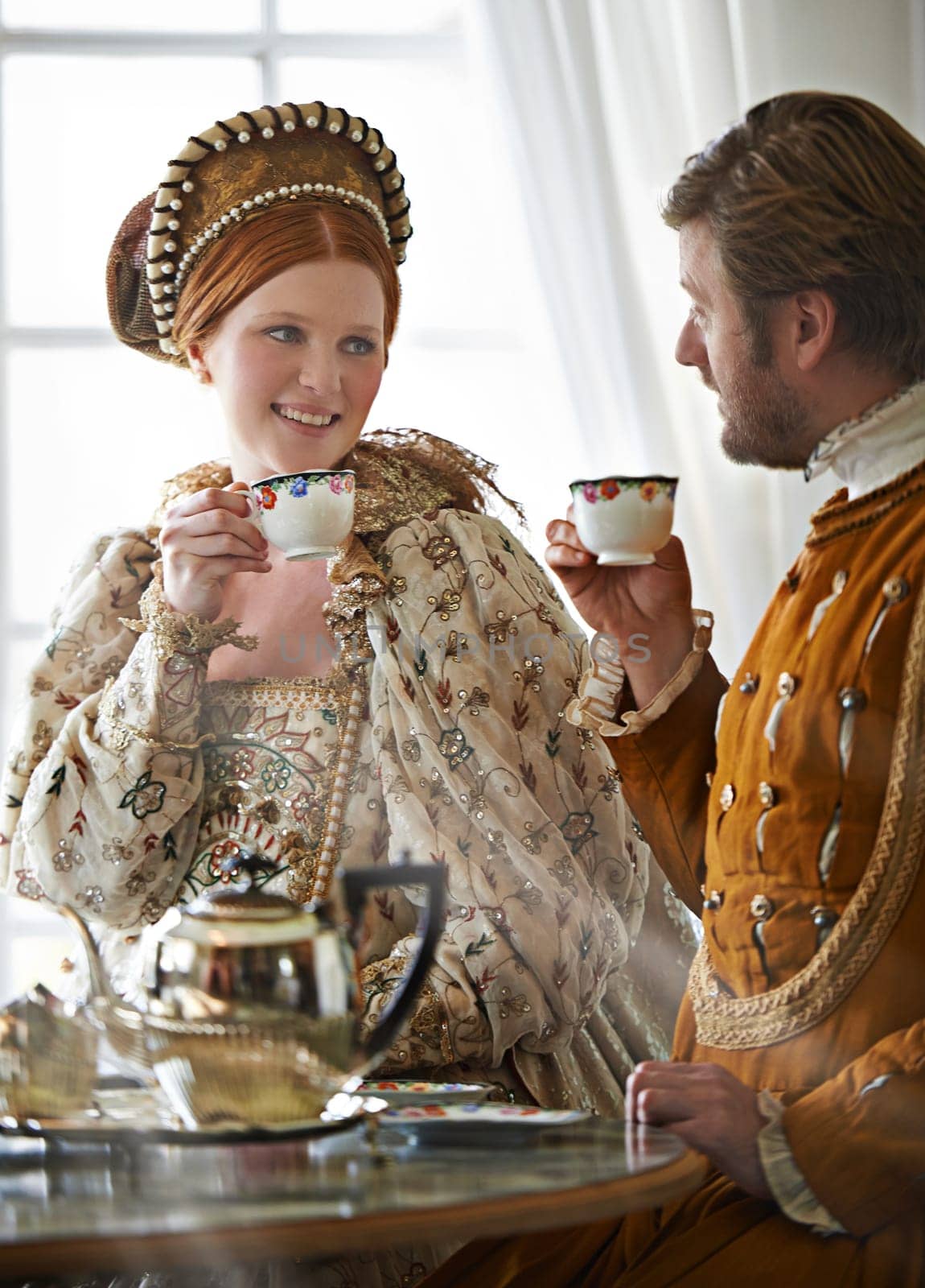 King, queen and couple with tea for royalty, smile and conversation in vintage clothes with style in castle. Woman, man and drink together in morning with Victorian fashion at regal palace in UK.