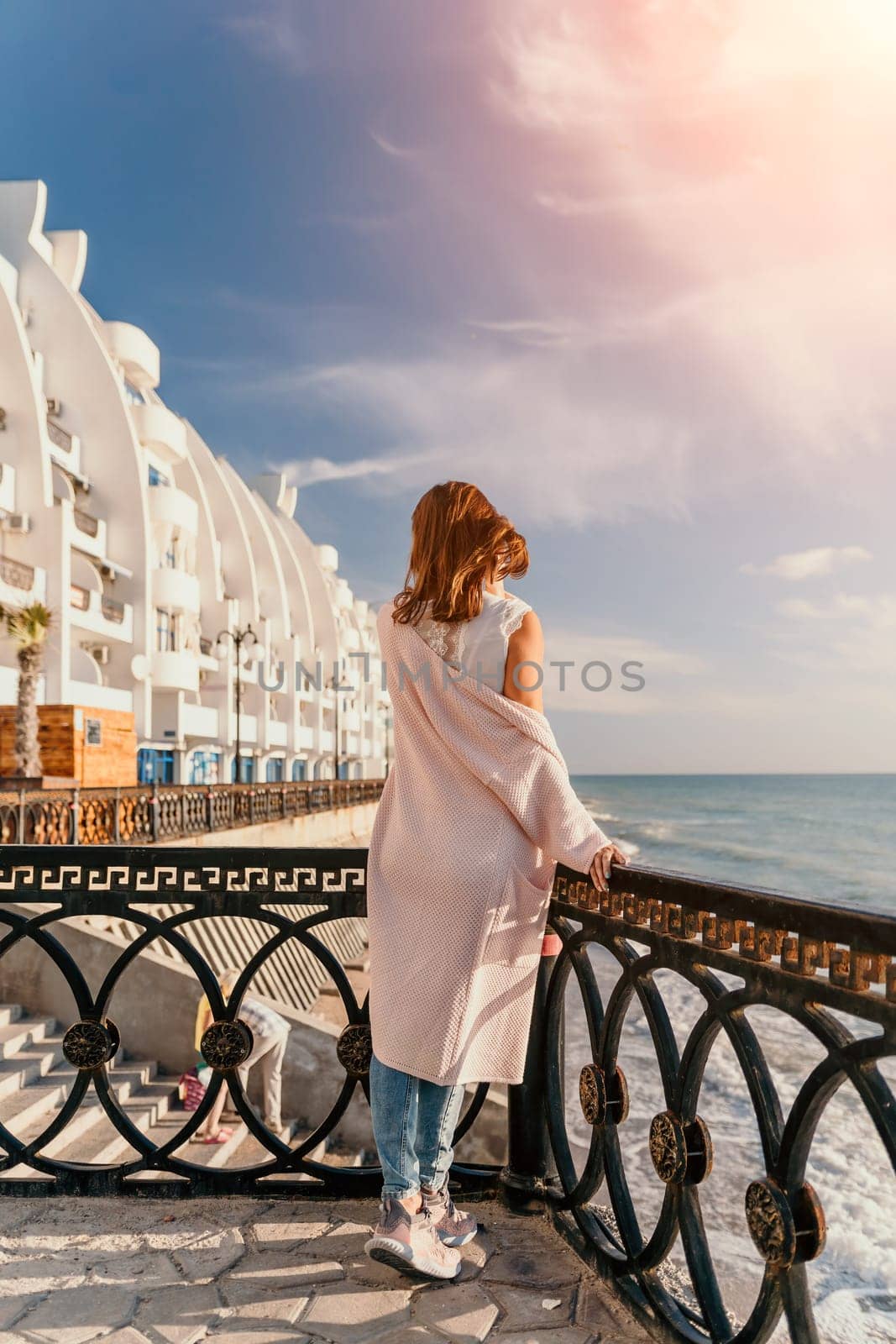 Woman travel sea. Young Happy woman in a long red dress posing on a beach near the sea on background of volcanic rocks, like in Iceland, sharing travel adventure journey