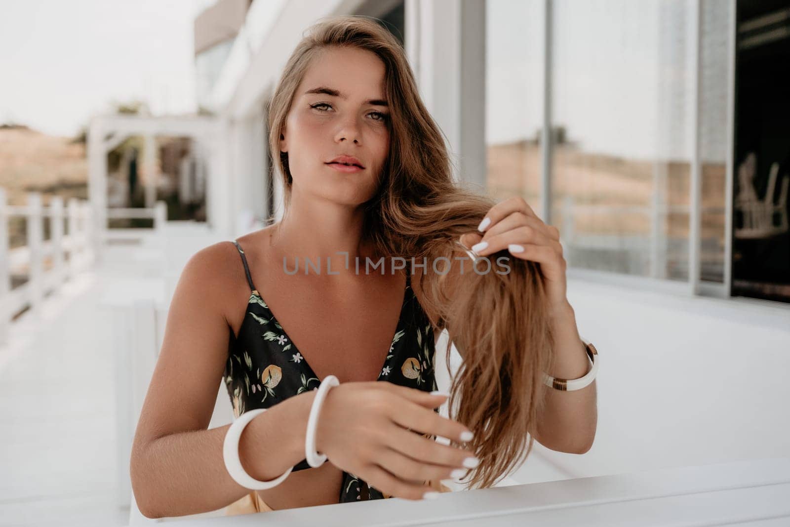 Happy woman portrait in cafe. Boho chic fashion style. Outdoor photo of young happy woman with long hair, sunny weather outdoors sitting in modern cafe