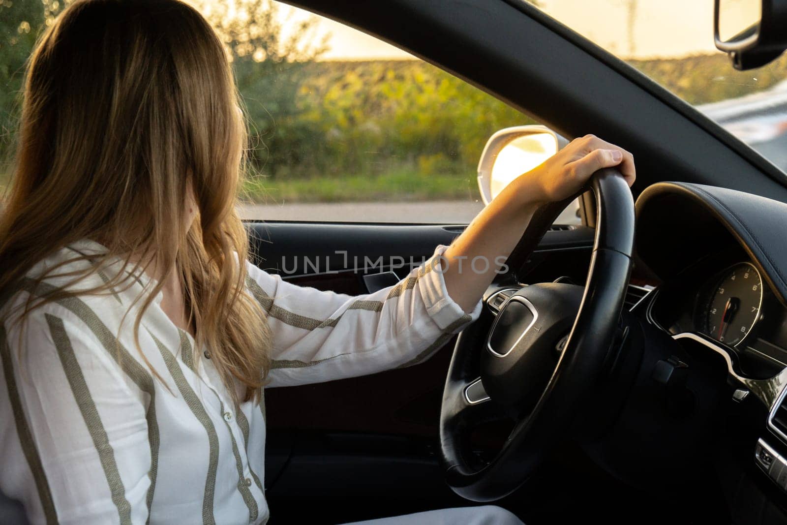 Young woman parking while driving car on highway road during sunset. Womandriver looking for help. Business woman busy driving by anna_stasiia
