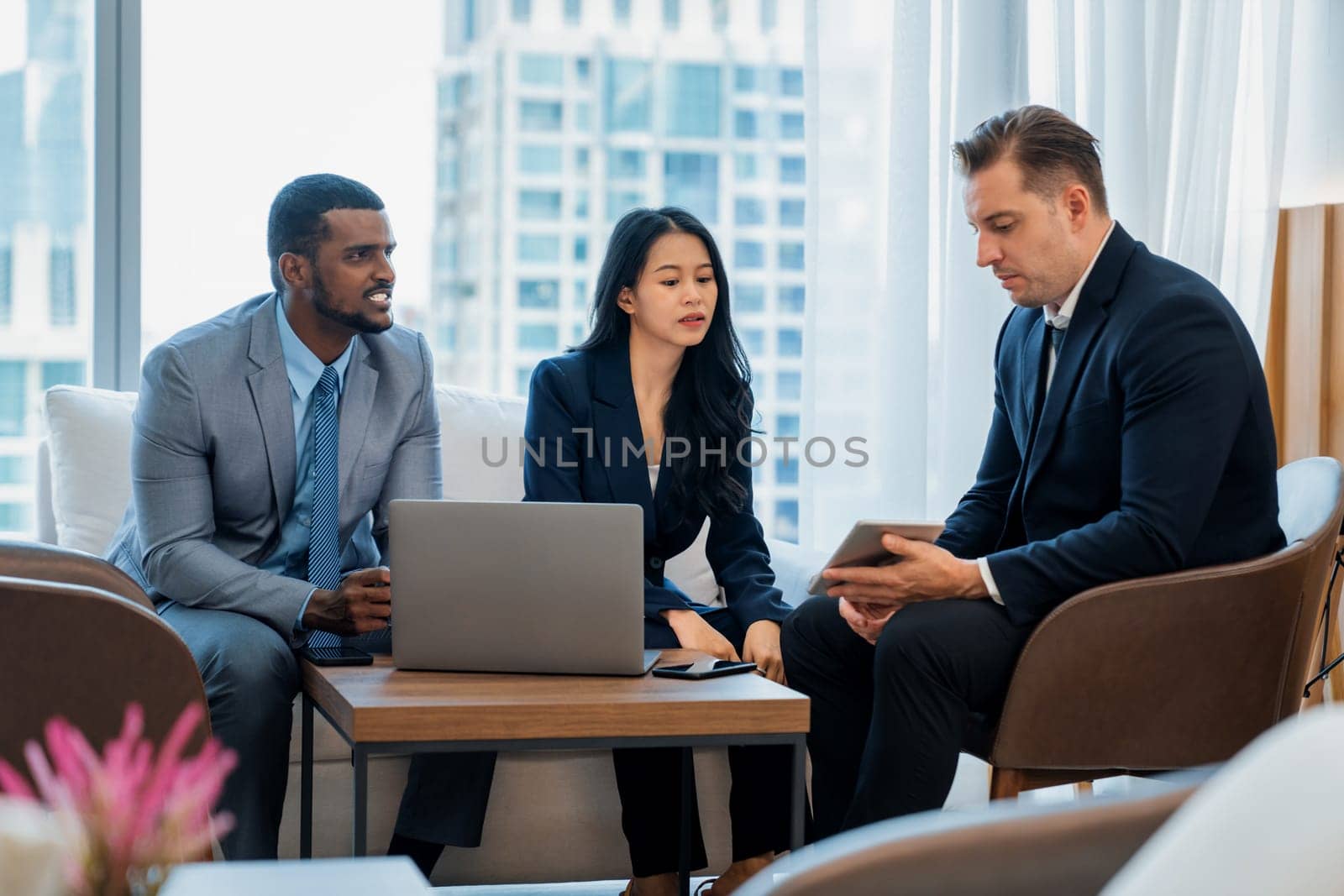 Smart caucasian businessman present marketing idea by using tablet. Group of business team listening while deciding to invest in start up project at modern lounge. Ornamented.