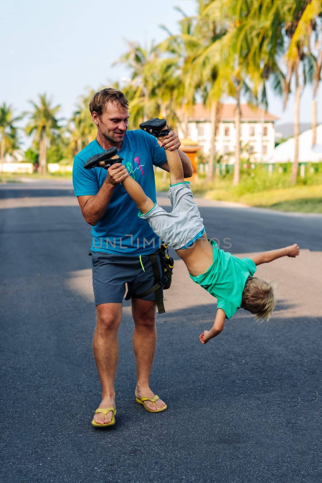 Father son have fun. Man holds child's leg upside down head. Joy happiness childhood paternity delight.