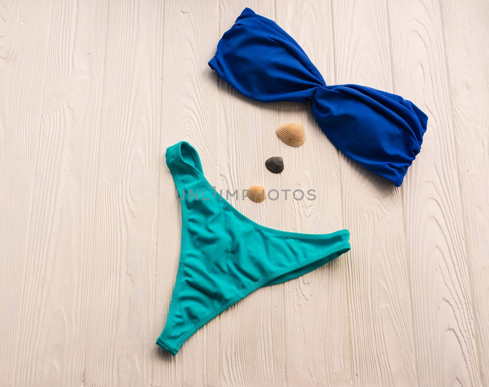 Women split multicolor blue swimsuit bikini. Summer background mockup template. pattern top view above swimwear white wooden background. accessories clothes beach. Women summer design vacation