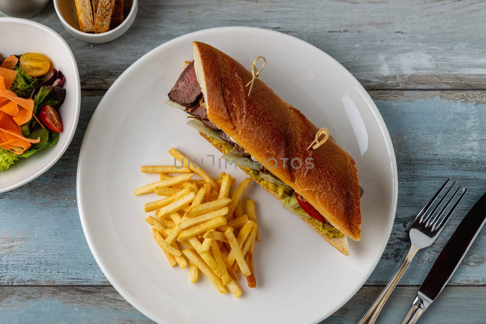 Grilled steak sandwich with french fries on a white porcelain plate by Sonat