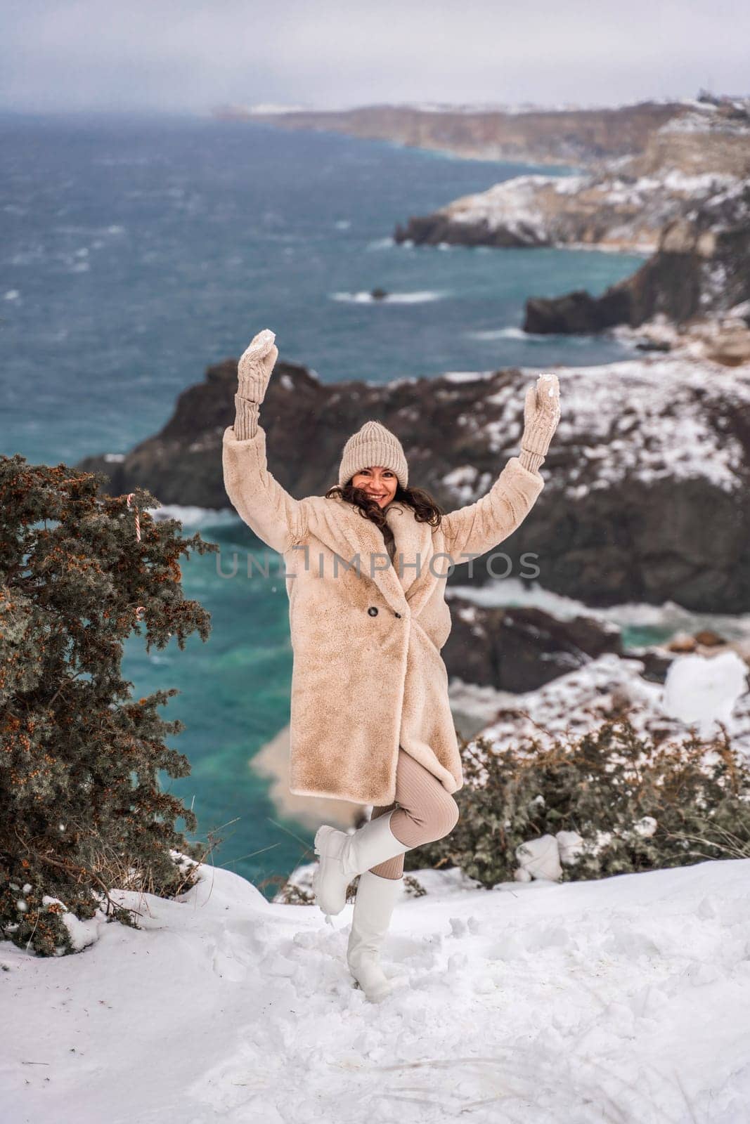 Woman snow sea. Amidst a wintry backdrop, a woman in a beige faux fur coat gleefully engages in a snowball fight, adding joy to the serene seascape