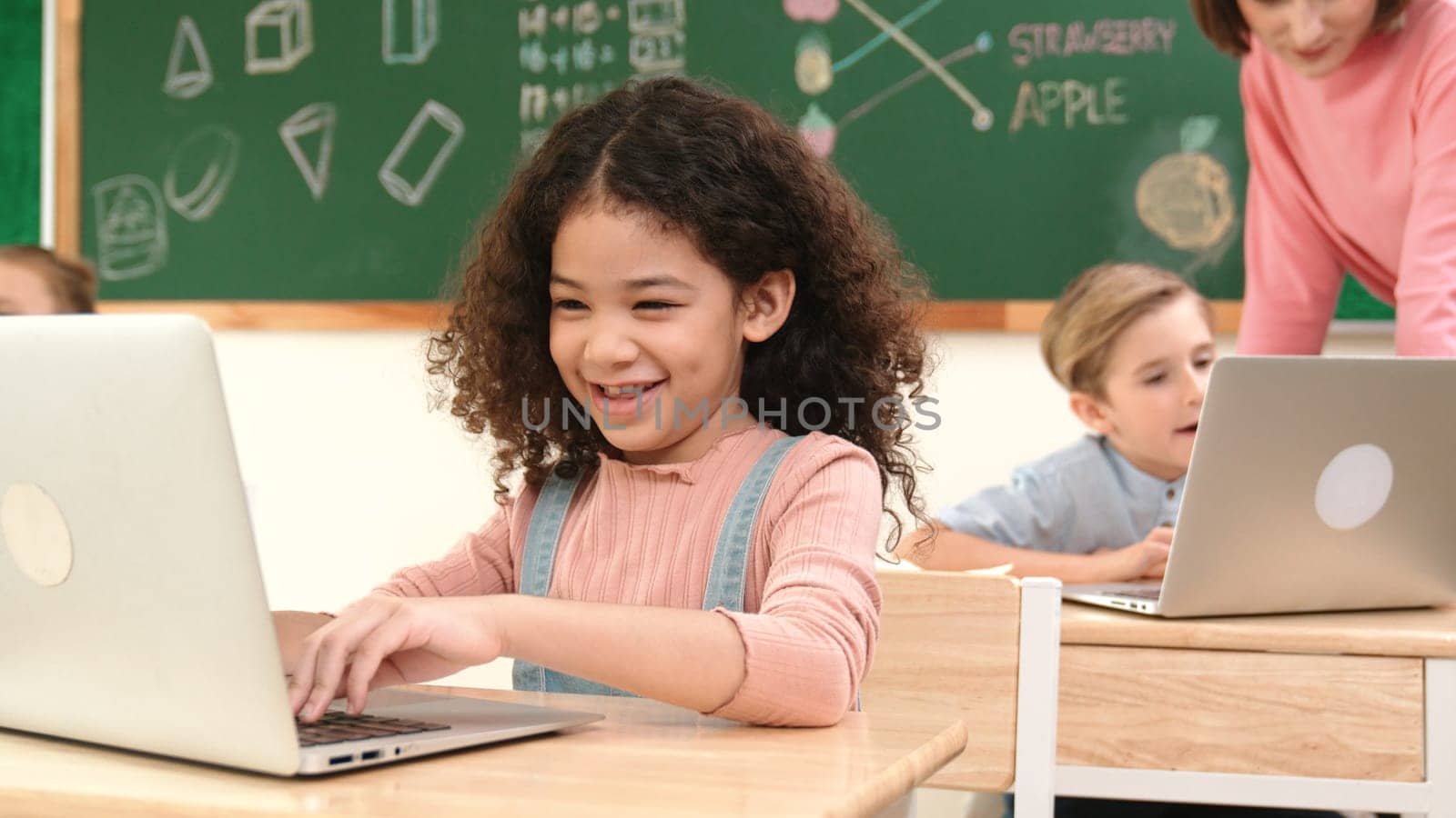 Attractive girl coding prompt while looking at camera at STEM class while happy teacher checking smart boy software program. Diverse student study about programing code and computing system. Pedagogy.