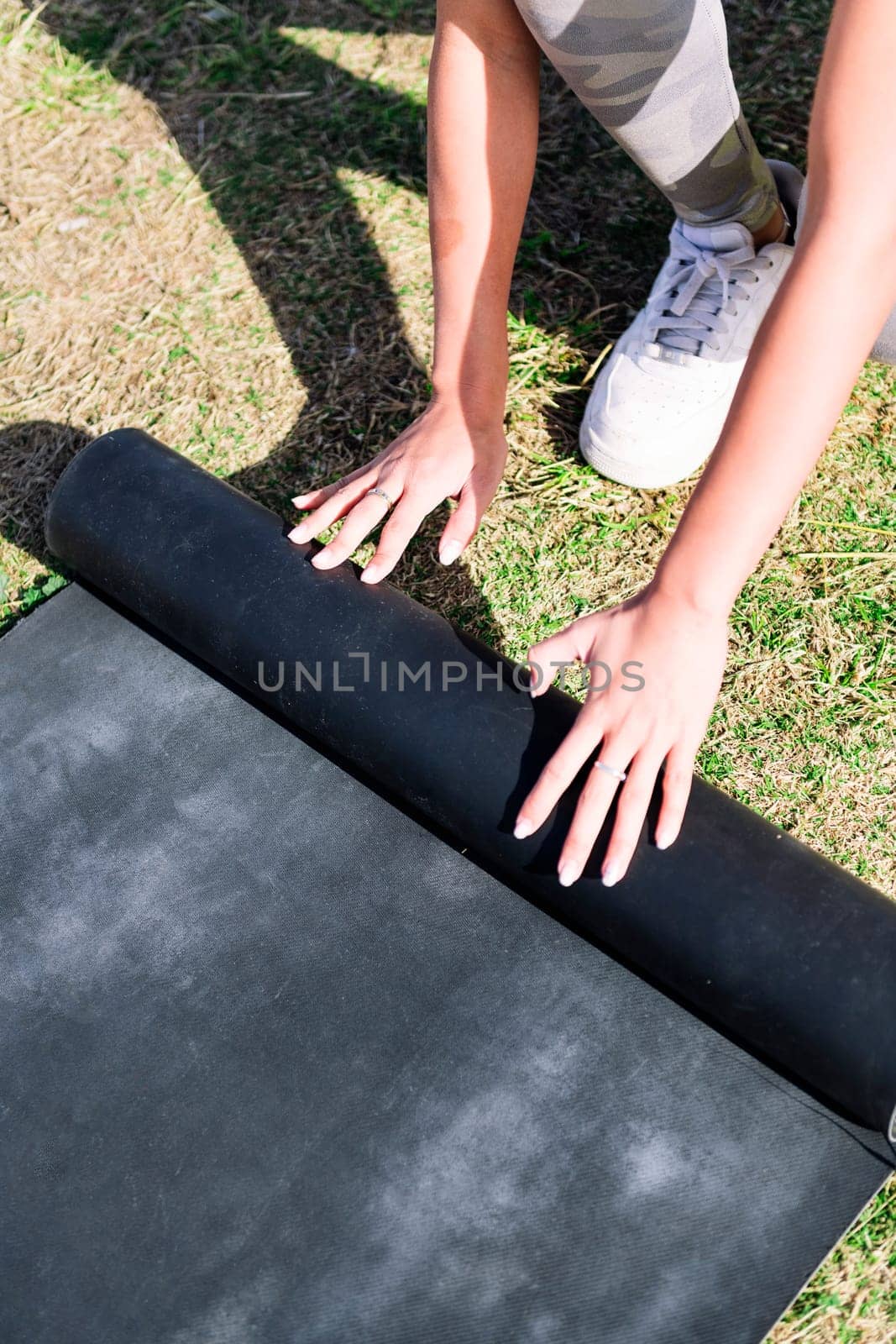 hands of an unrecognizable young woman rolling mat for a yoga session on the grass in the park, healthy and active lifestyle concept