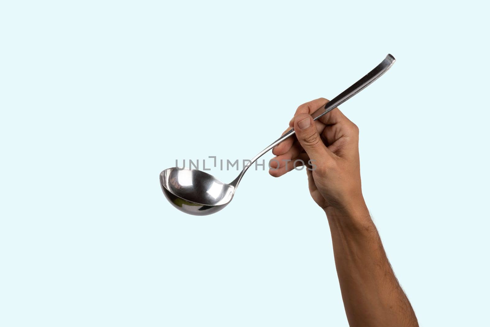 Black male hand holding a silver kitchen ladle isolated on cyan background. High quality photo