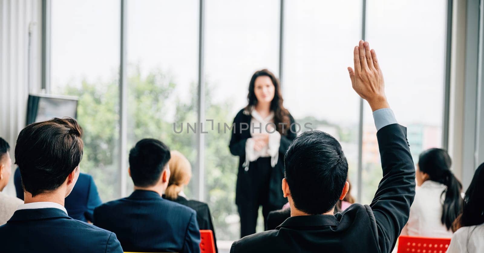 One individual among a group raises a hand in a conference demonstrating active participation teamwork and a willingness to engage in discussions. by Sorapop