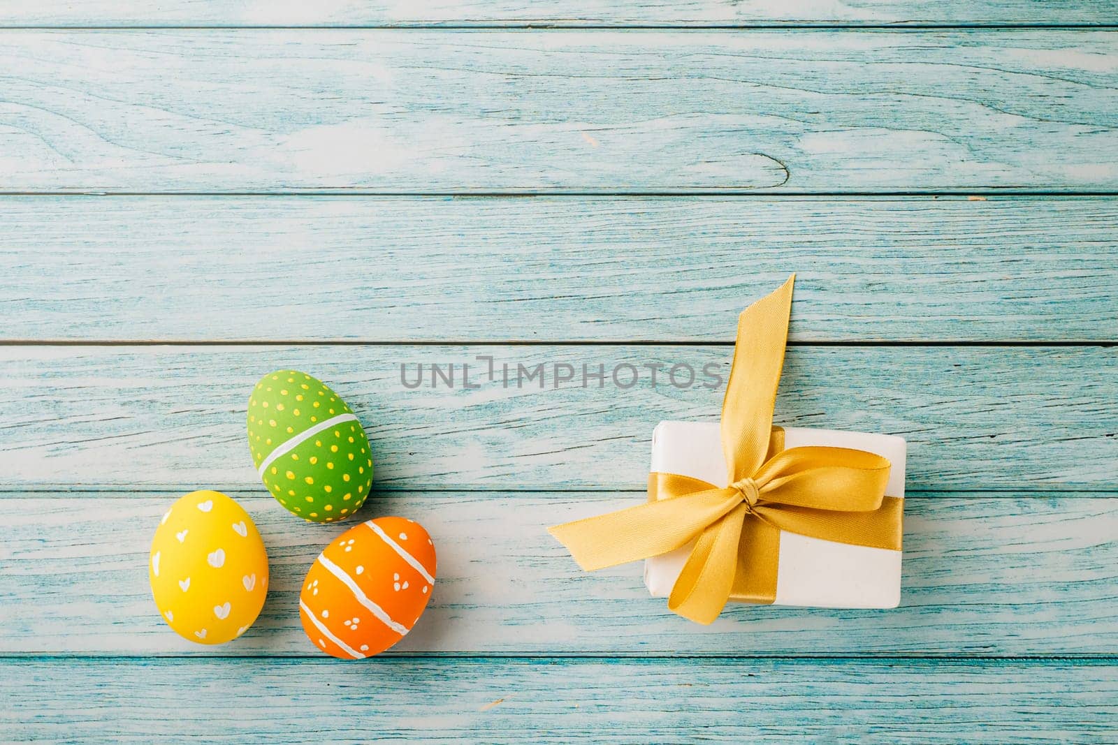 Happy Easter Day Concept. Top view holiday banner background design with easter colorful eggs and gift box on blue wooden background with copy space
