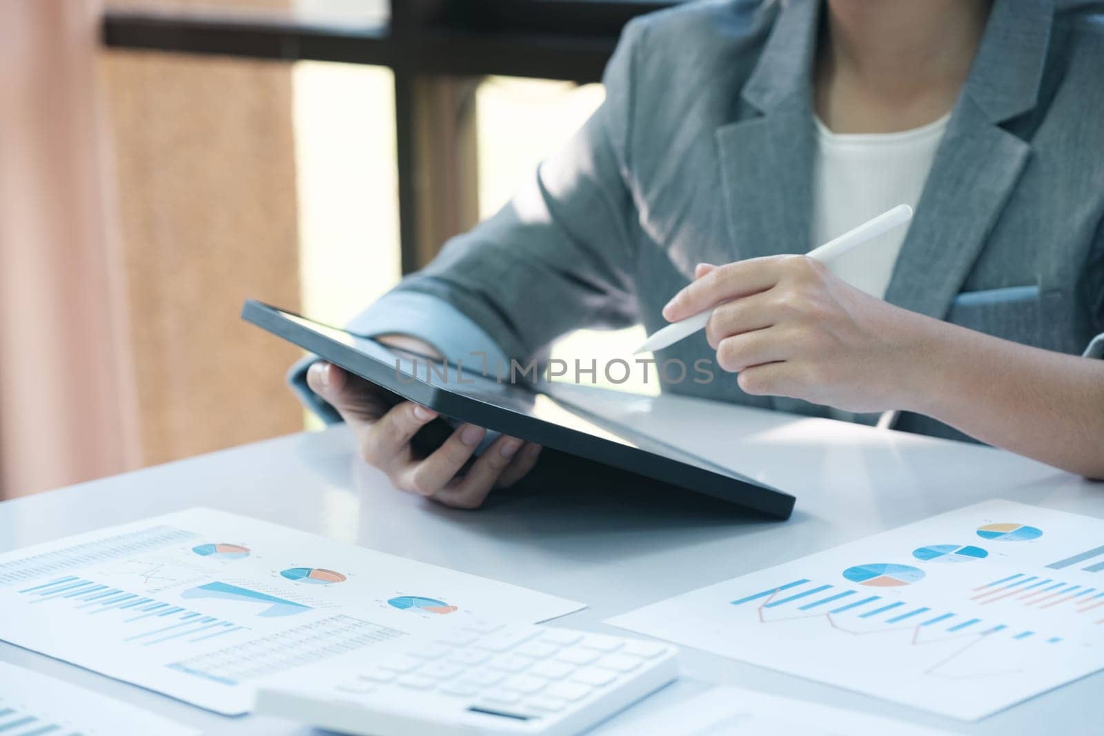 A woman is sitting at a desk with a tablet and a pen by ijeab