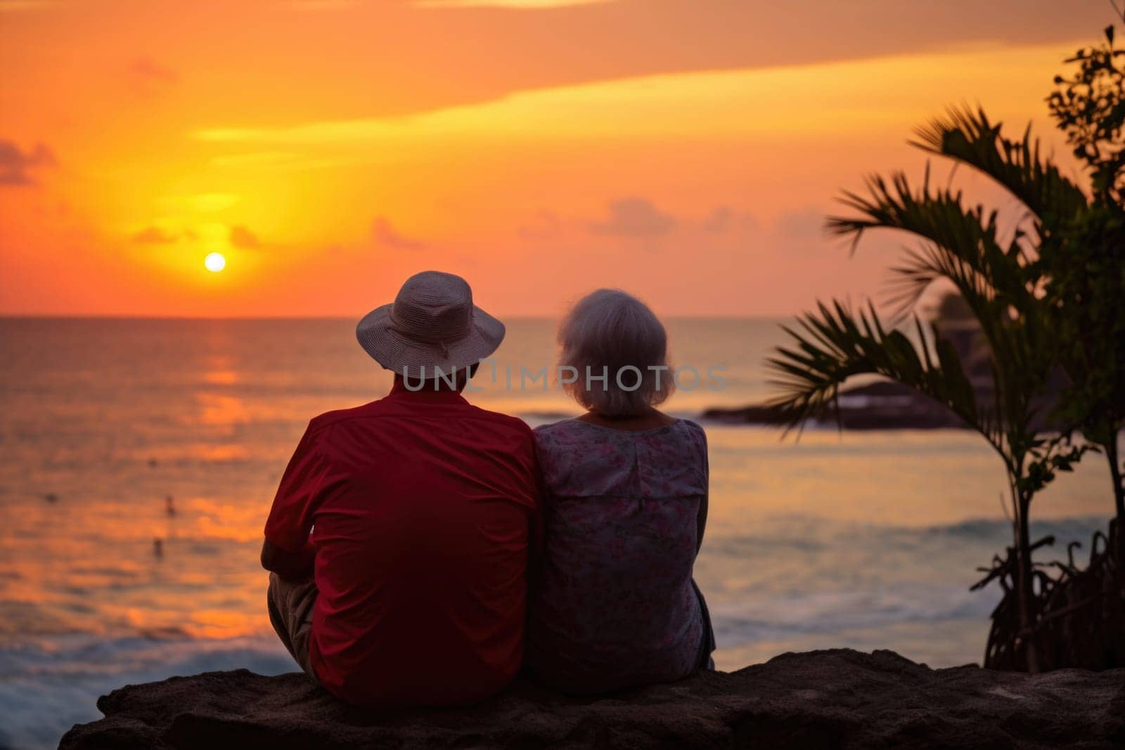 Silhouette of an elderly couple waiting for a colorful sunset sitting by the ocean by Lobachad