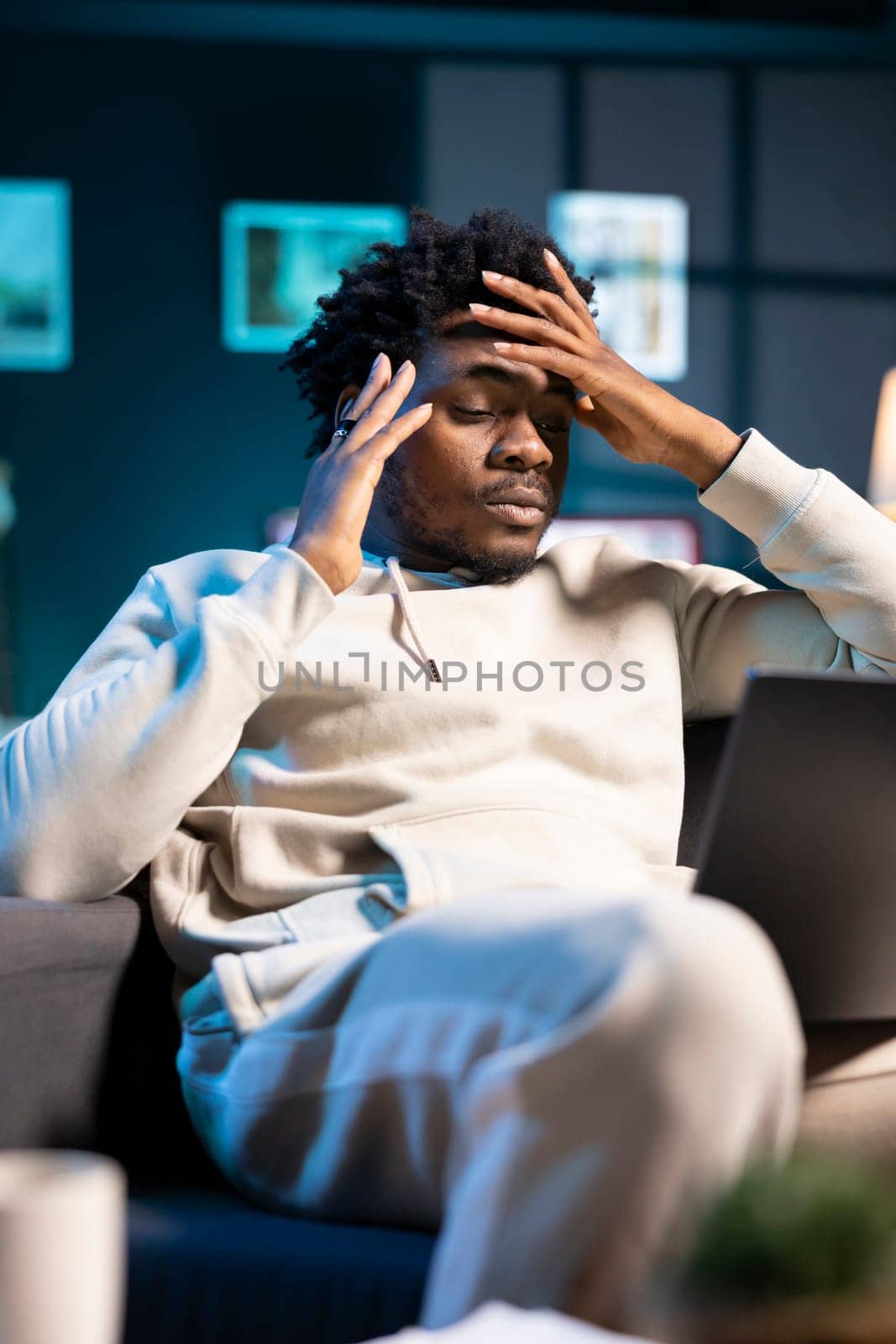 Anxious overworked man struggling to concentrate while working from home, hurting from severe headache. Tired teleworker exhausted after sleepless night, struggling to pay attention on tasks
