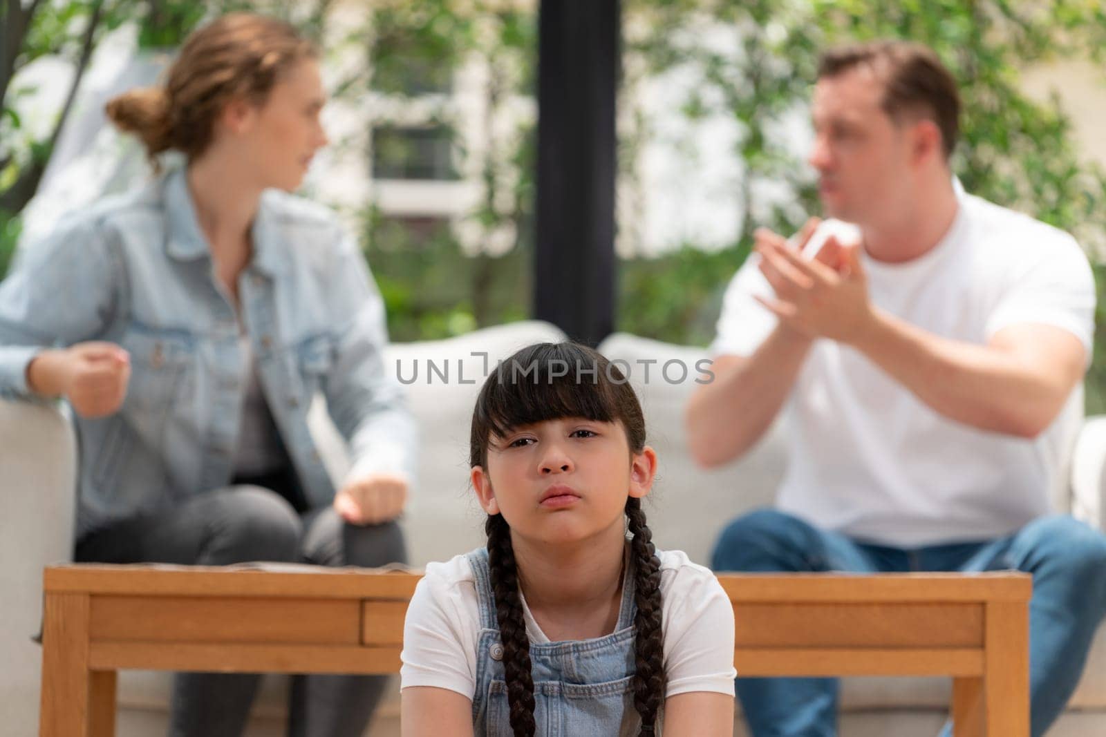 Stressed and unhappy young girl crying and trapped in middle of tension by her parent argument in living room. Unhealthy domestic lifestyle and traumatic childhood develop to depression. Synchronos