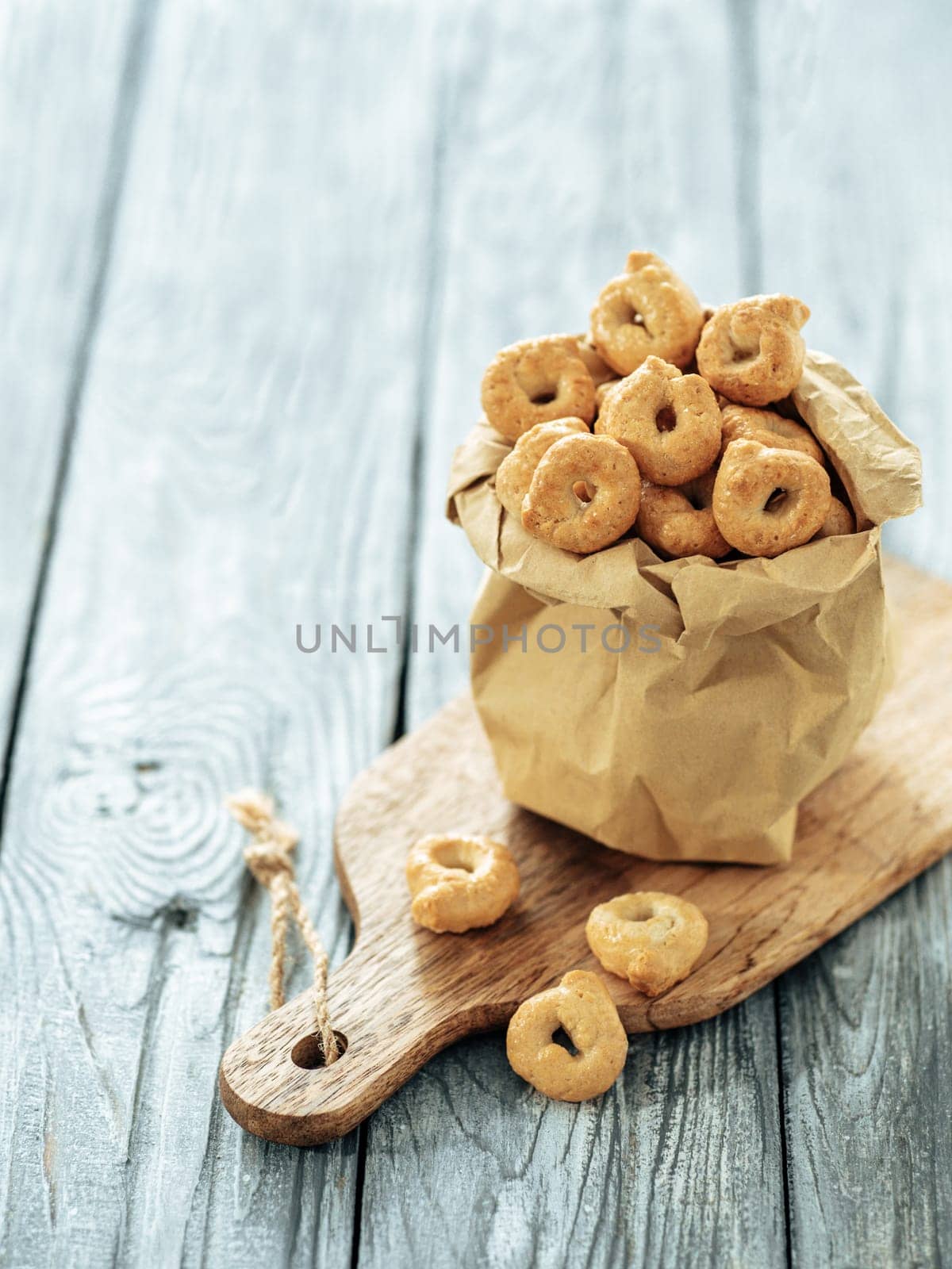 Traditional italian snack taralli or tarallini in paper bag over old gray wooden table. Rustic shot of taralli appetizer with copy space