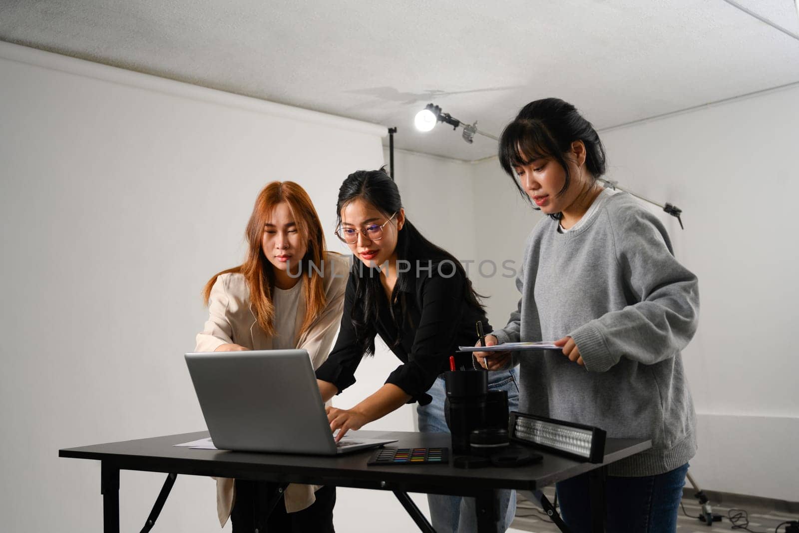 Young creative people using laptop working together in a professional studio.