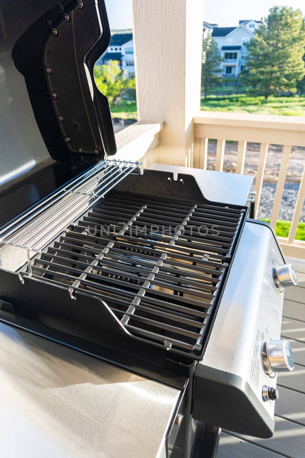Sleek, open-lid, two-burner grill stands ready for use, conveniently positioned on the balcony of a suburban home, promising a delightful alfresco cooking experience.