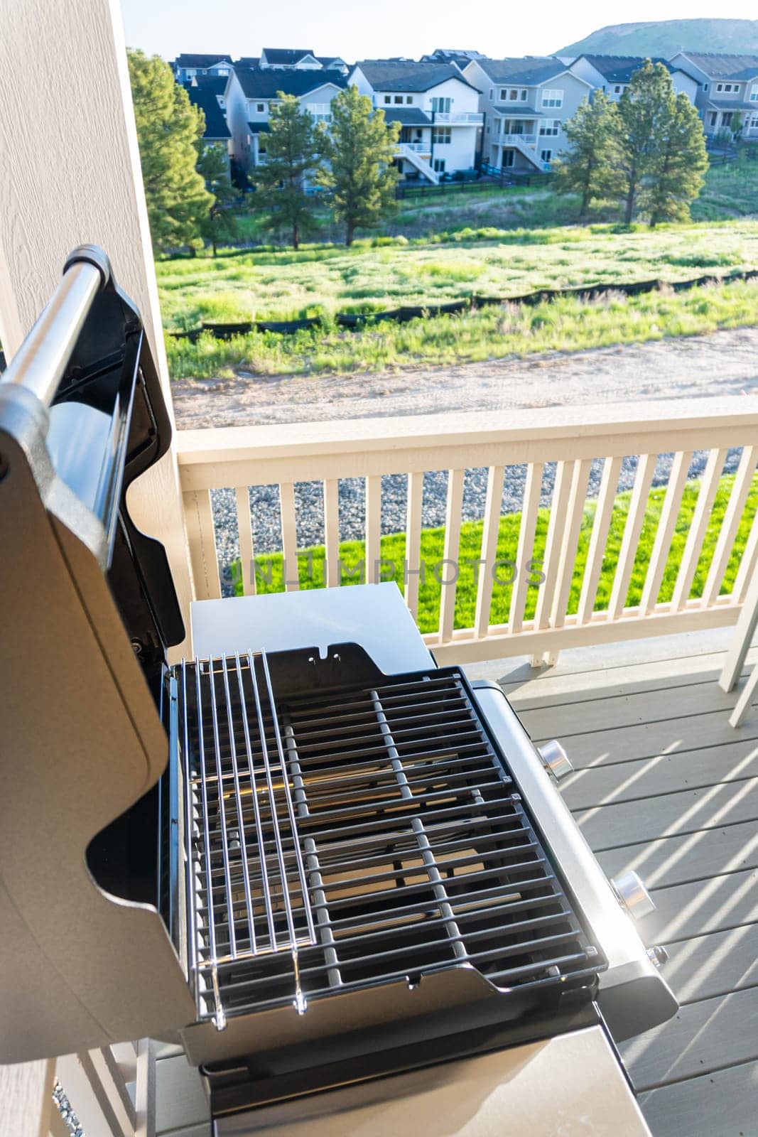 Sleek, open-lid, two-burner grill stands ready for use, conveniently positioned on the balcony of a suburban home, promising a delightful alfresco cooking experience.