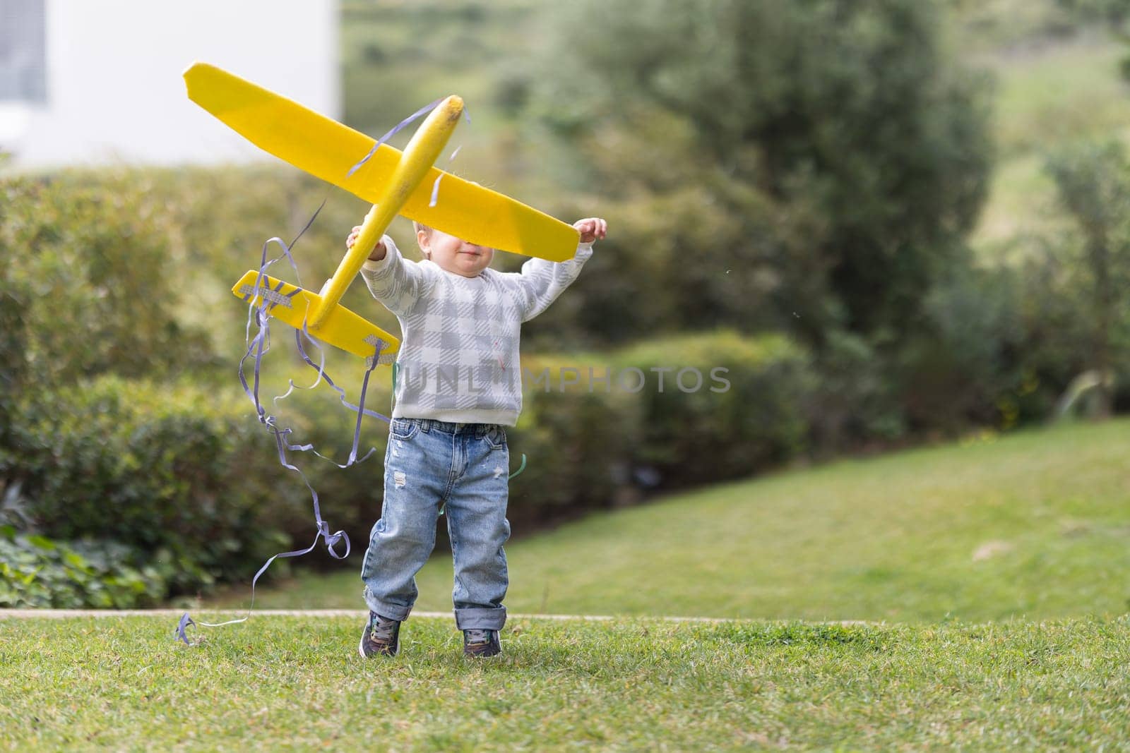 Boy toddler plays with toy model of airplane in park by Studia72