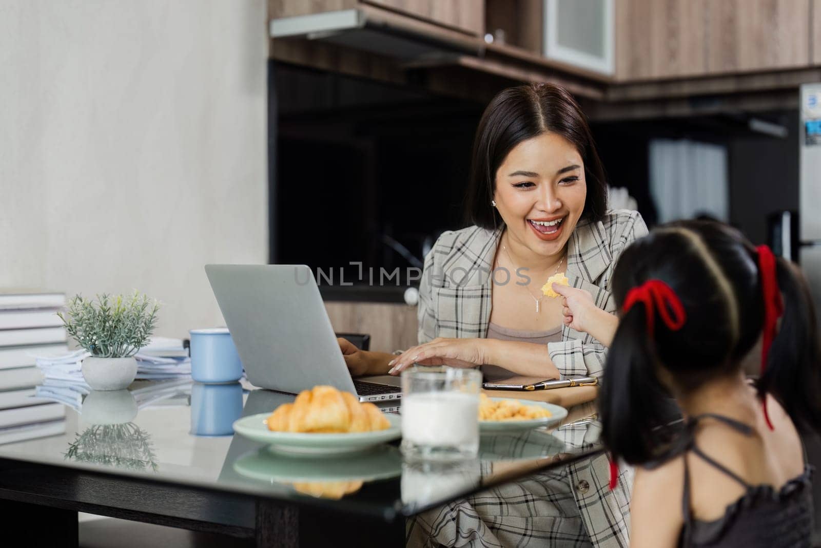 Business woman working from home and her child giving her snacks while working.