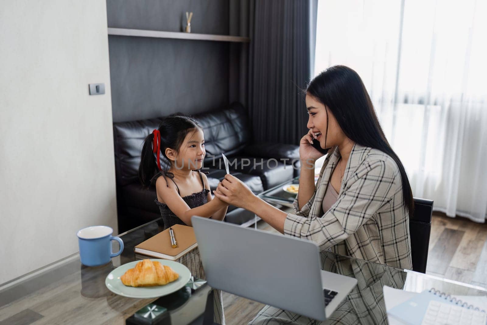 business woman work from home and take care of her child while working, doing activities with her child while talking on mobile by itchaznong