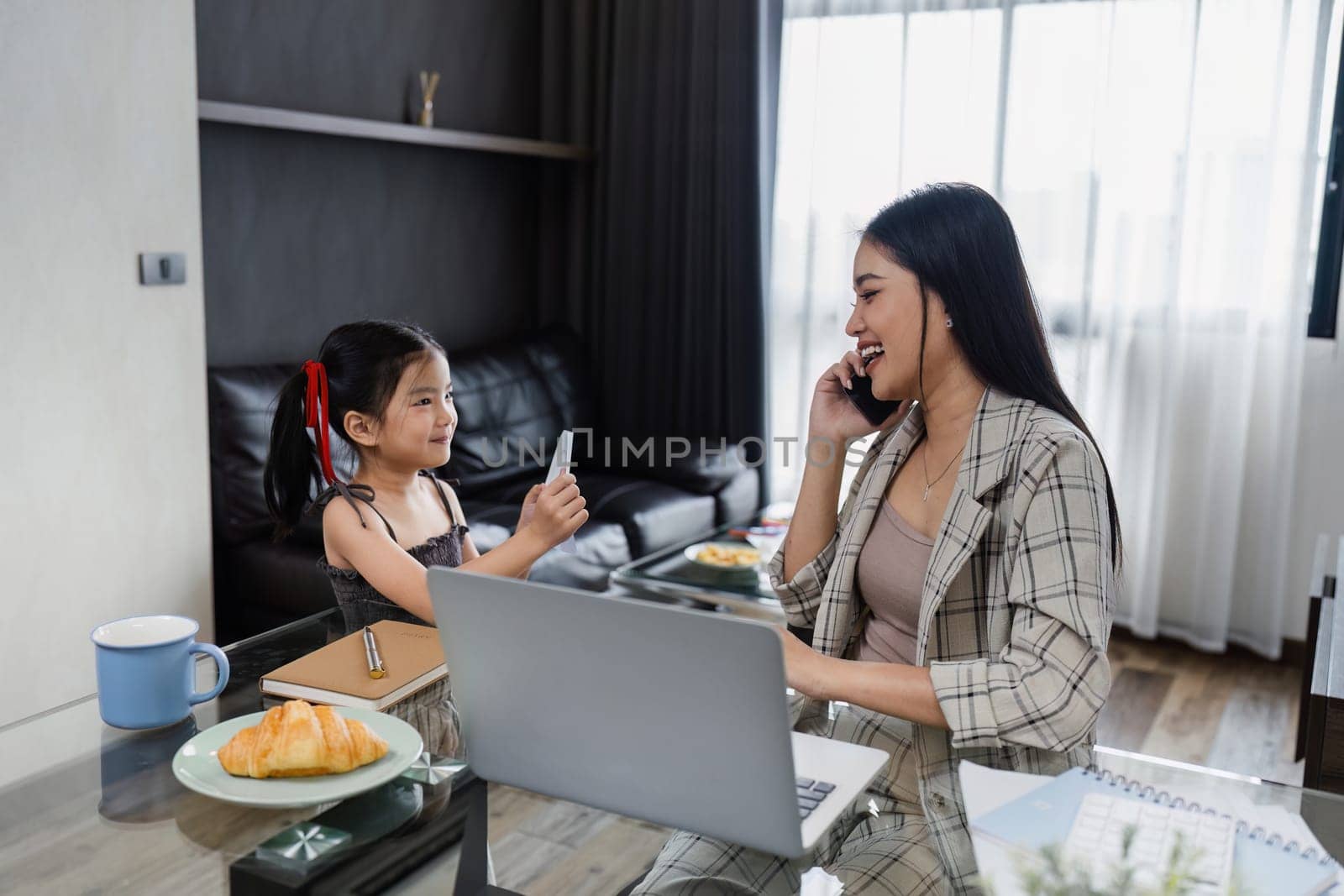 business woman work from home and take care of her child while working, doing activities with her child while talking on mobile by itchaznong