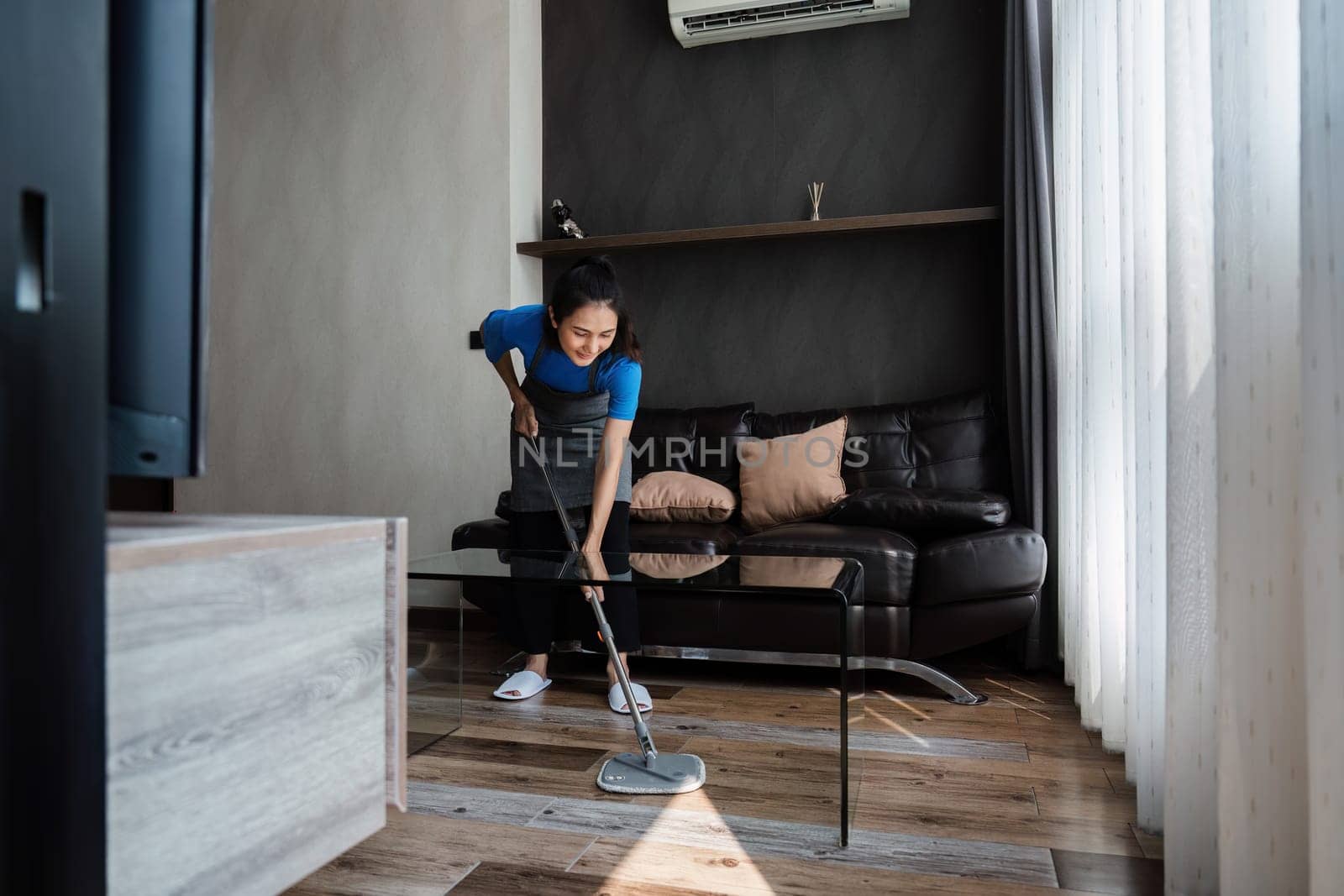 cleaning service housekeeper women swipe floor in living room. House cleaning service concept.