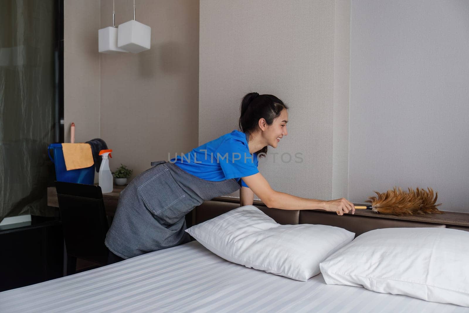 cleaning service woman worker clean bedroom at hotel. housekeeper cleaner feel happy and make bed look neat. housework and housekeeping cleaning service by itchaznong