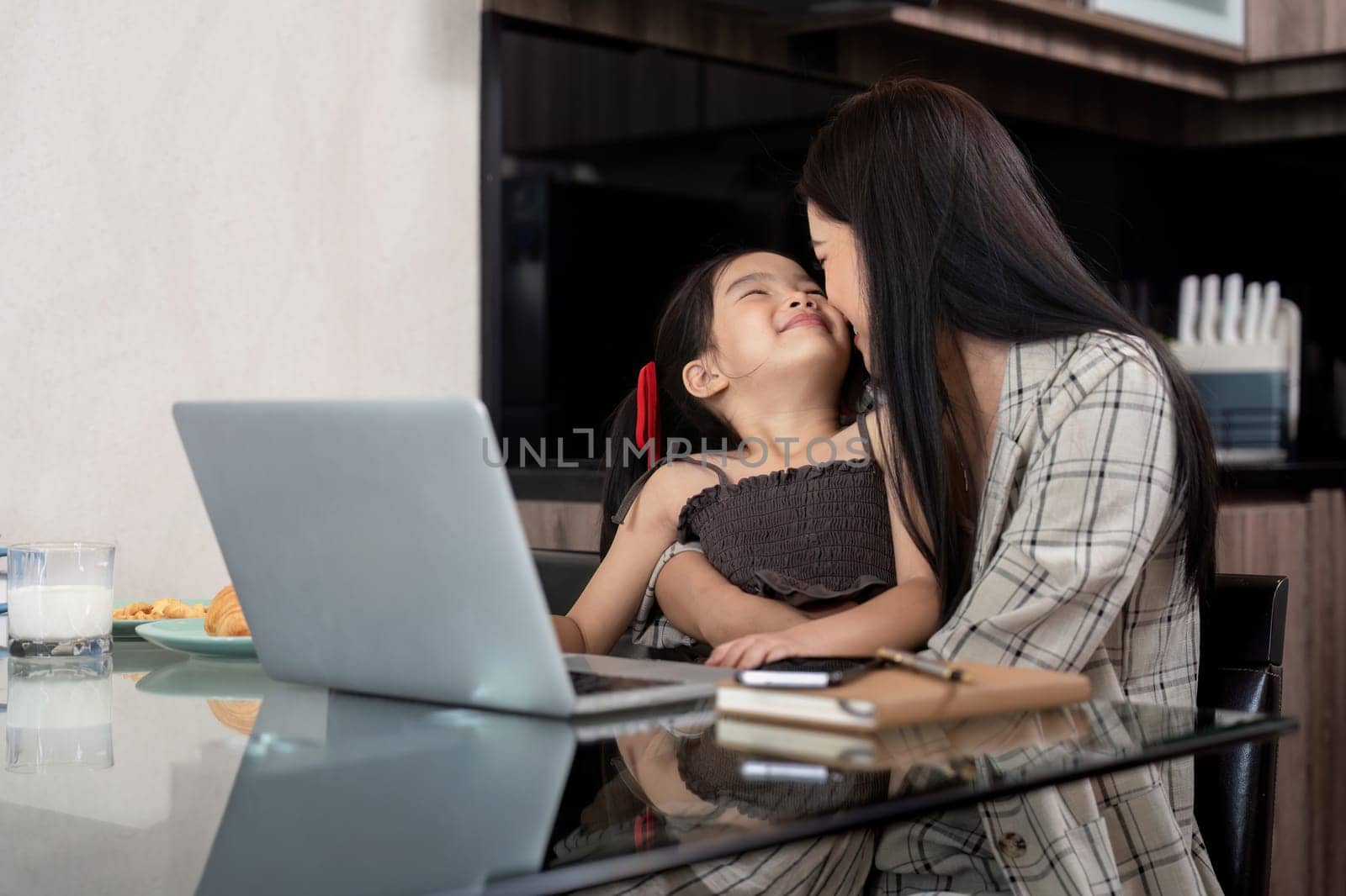 Business woman or mom working with her little daughter at a laptop. Freelance, work from home by nateemee