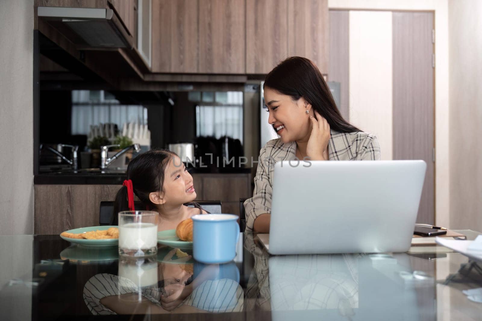 Working mom work from home office. Happy mother and daughter look to each other. businesswoman and cute child using laptop work freelancer workplace in cozy kitchen, Lifestyle by nateemee