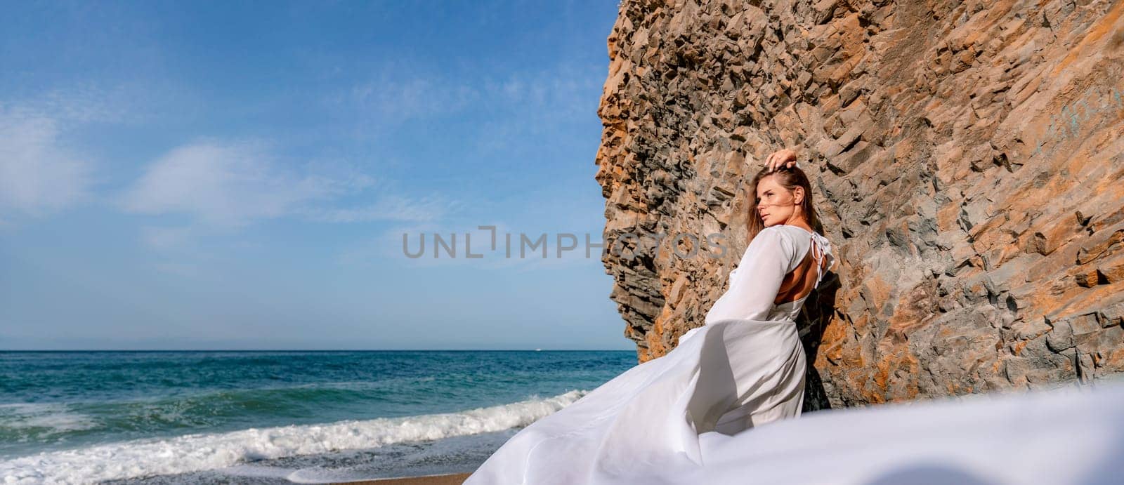 Woman beach white dress flying on Wind. Summer Vacation. A happy woman takes vacation photos to send to friends. by Matiunina