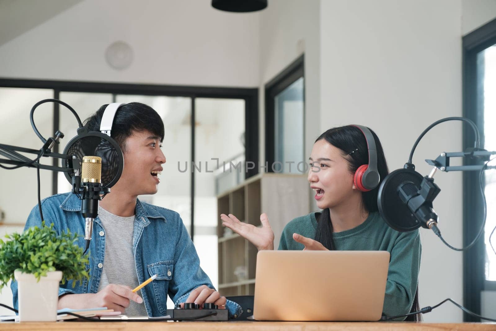 Two people are talking on a microphone. One of them is wearing headphones. The other person is wearing a green shirt