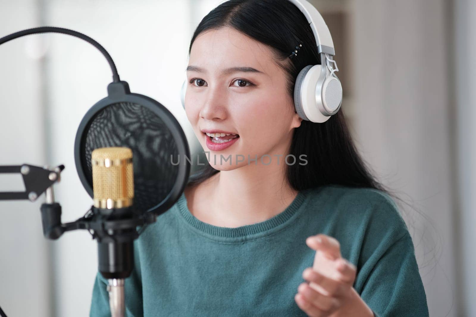 A woman is singing into a microphone. She is wearing headphones and has a microphone in front of her