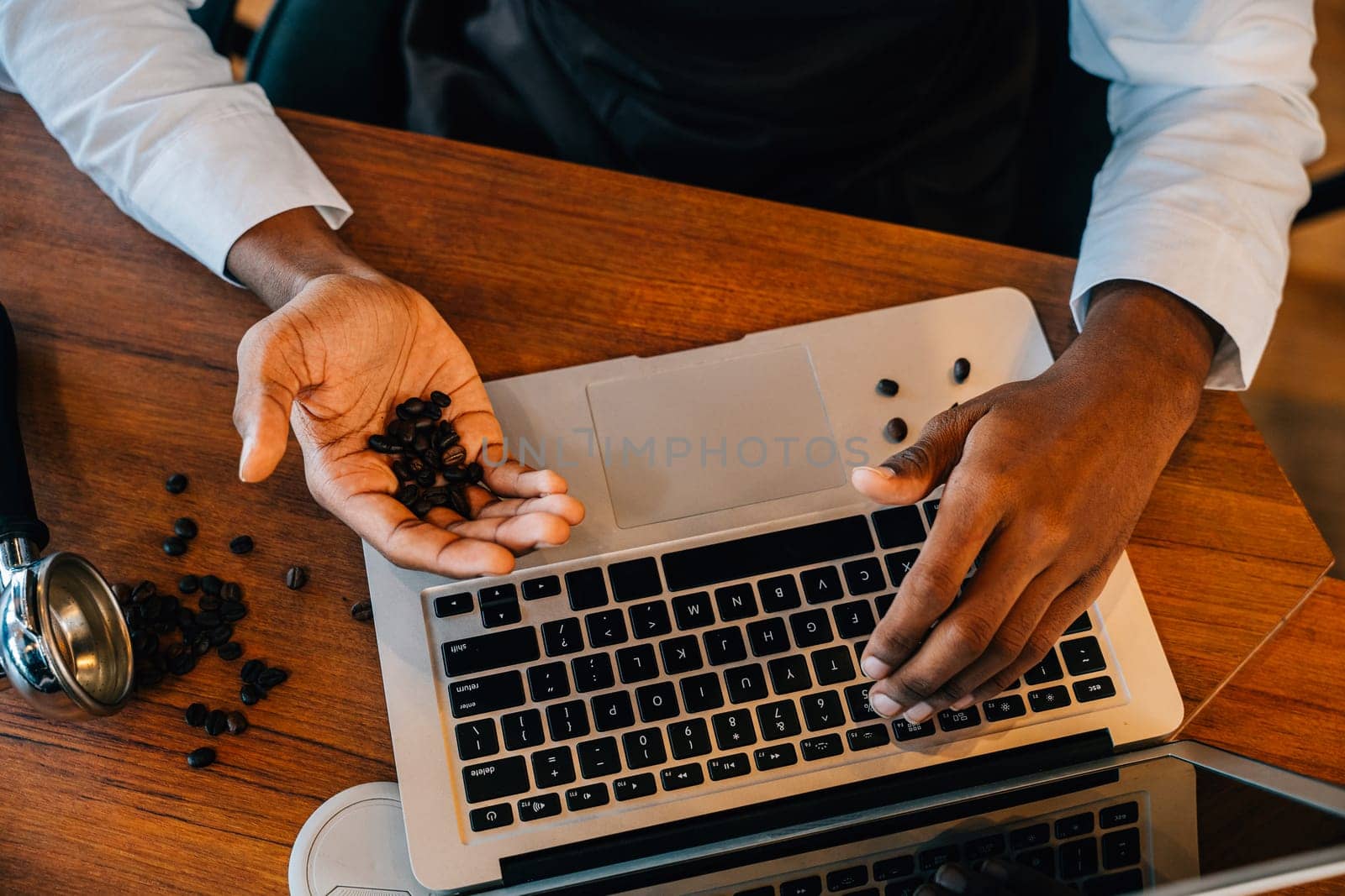 At coffee roastery the business owner and barista utilizes laptop to verify bean quality. With meticulous checks and technology ensuring premium beans is key. Business owner verification is evident. by Sorapop