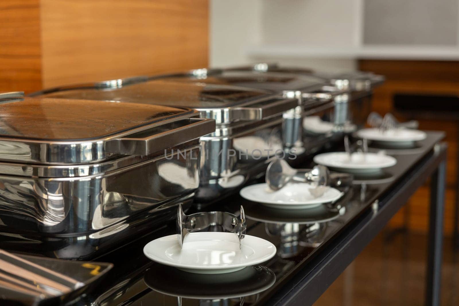 Row of closed chafing dishes at party banquet hall. Marmites ready for service made of stainless steel at buffet.