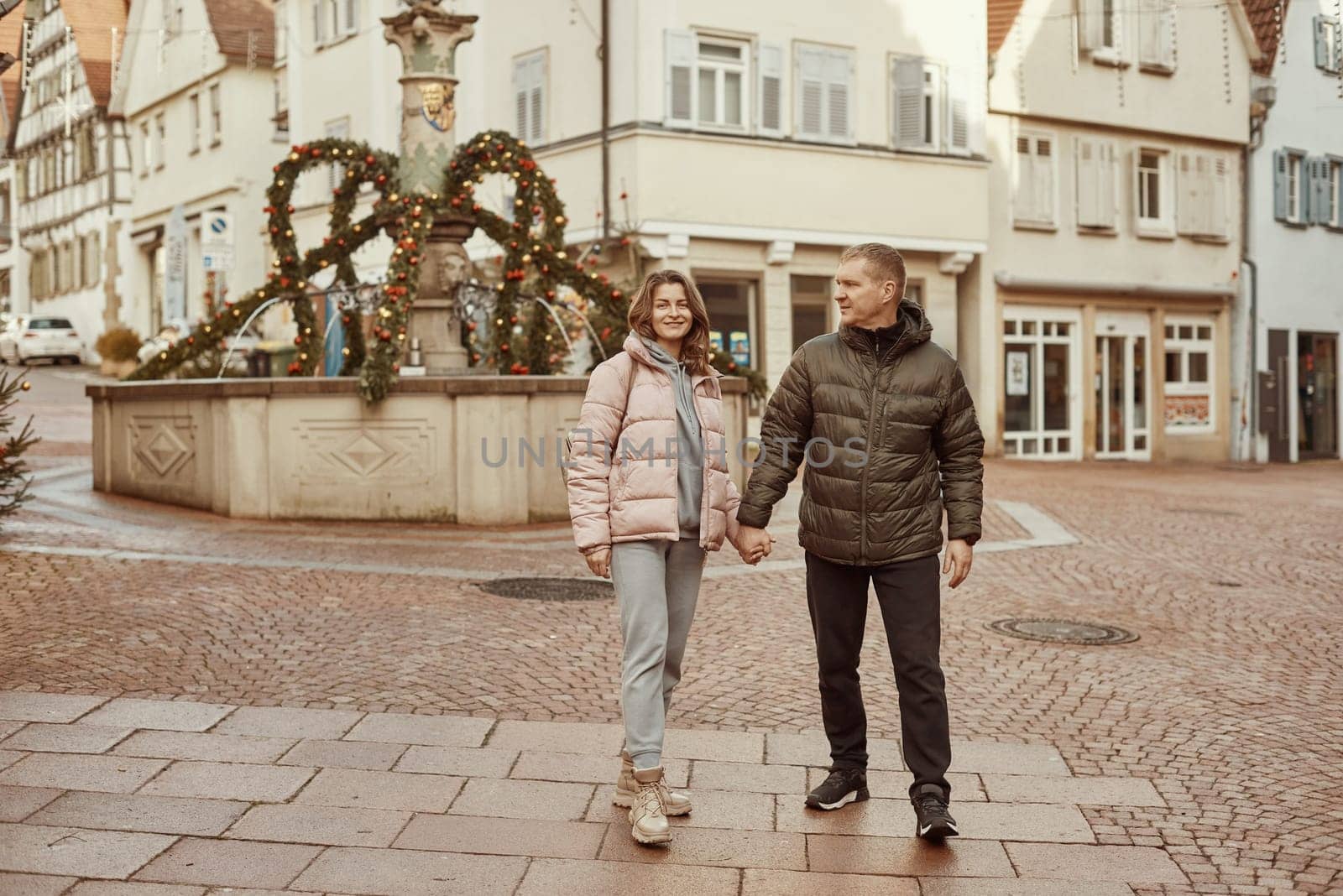 Loving couple of tourists walking around old town. Man woman couple walking europe old town Germany. Couple of lovers leisurely stroll in the cool autumn morning on the streets of a BIETIGHEIM-BISSINGEN (Germany). The guy holds his wife. Vacation, autumn, holiday. Couple Walking in Europe's Old Town
