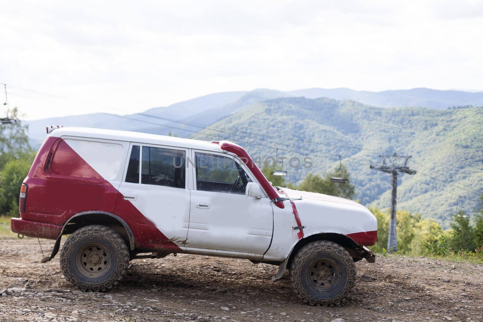 Old four-wheel drive vehicles driving on rocky mountain road on background volcanic landscape by Andelov13