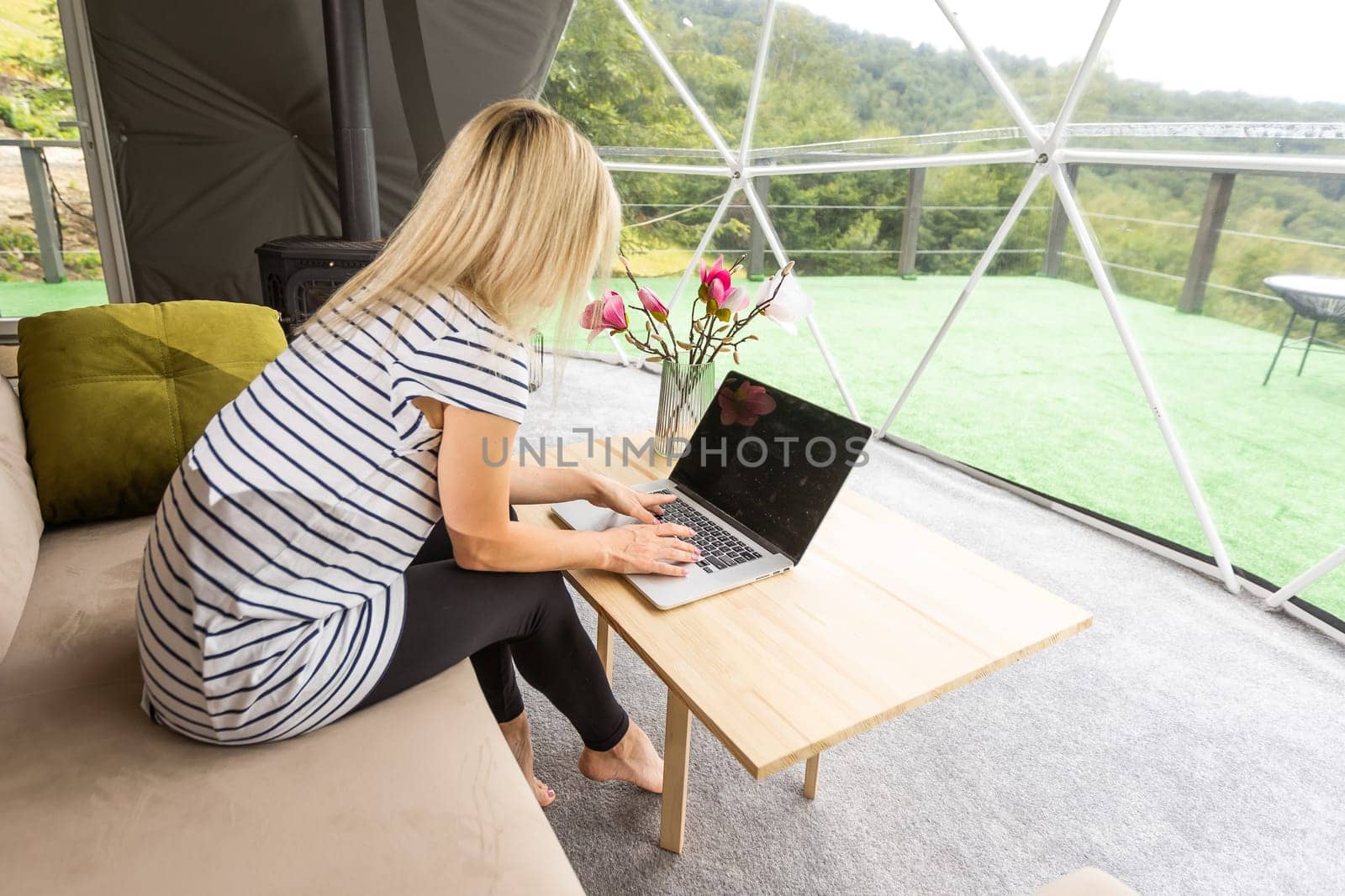 Young caucasian woman using and watching on laptop computer on in dome camping hotel. Tourism, vacation and weekend. by Andelov13
