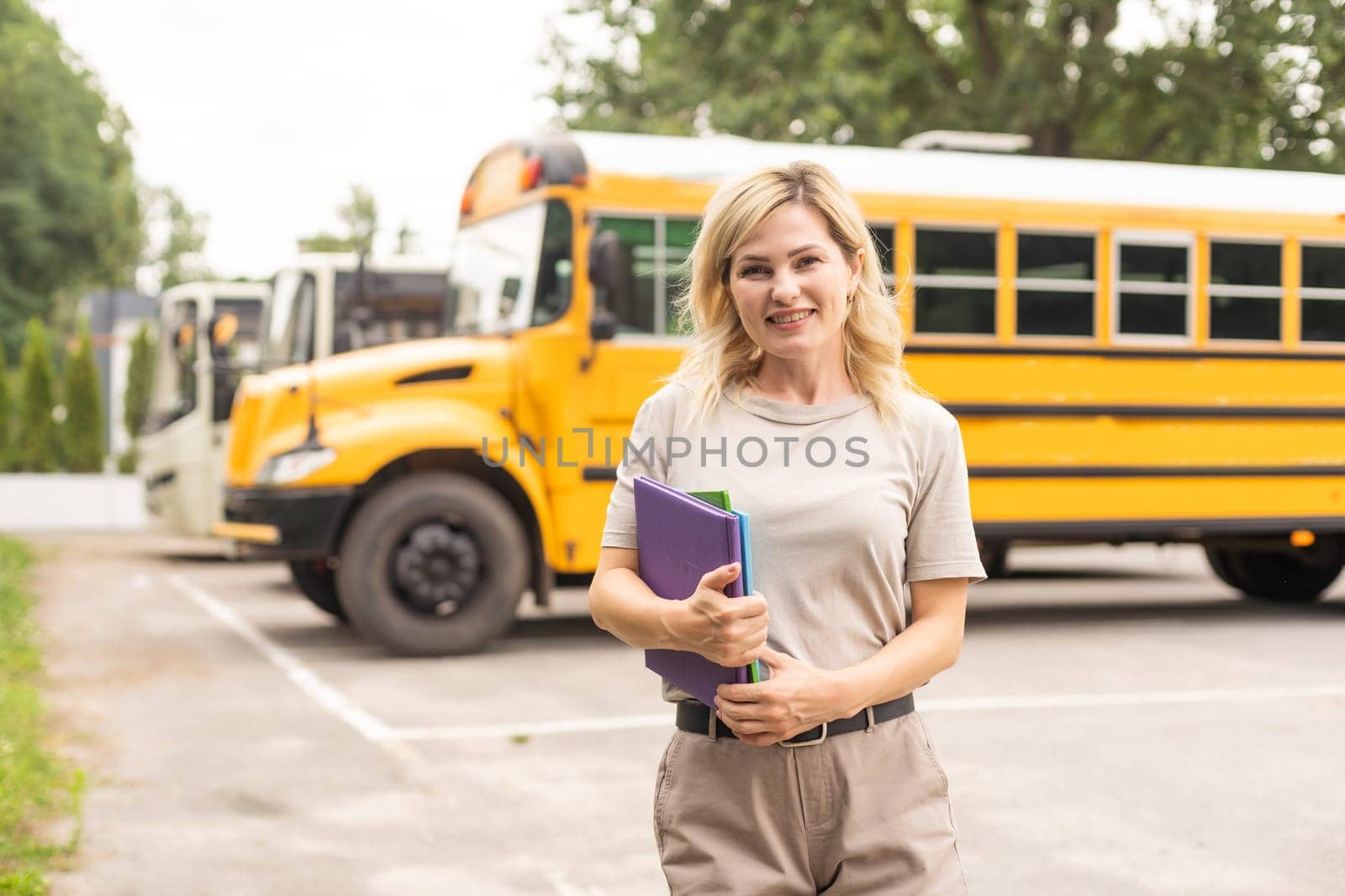 Portrait of cheerful teacher standing near the school bus