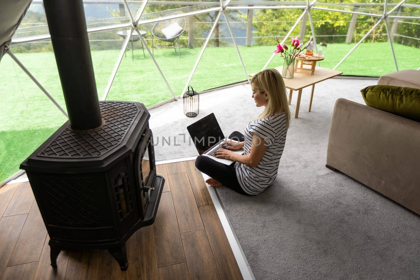 middle aged woman uses a laptop resting and spending time at Glamping house on holidays. holiday dome tent. Cozy, camping, hygge, lifestyle concept by Andelov13