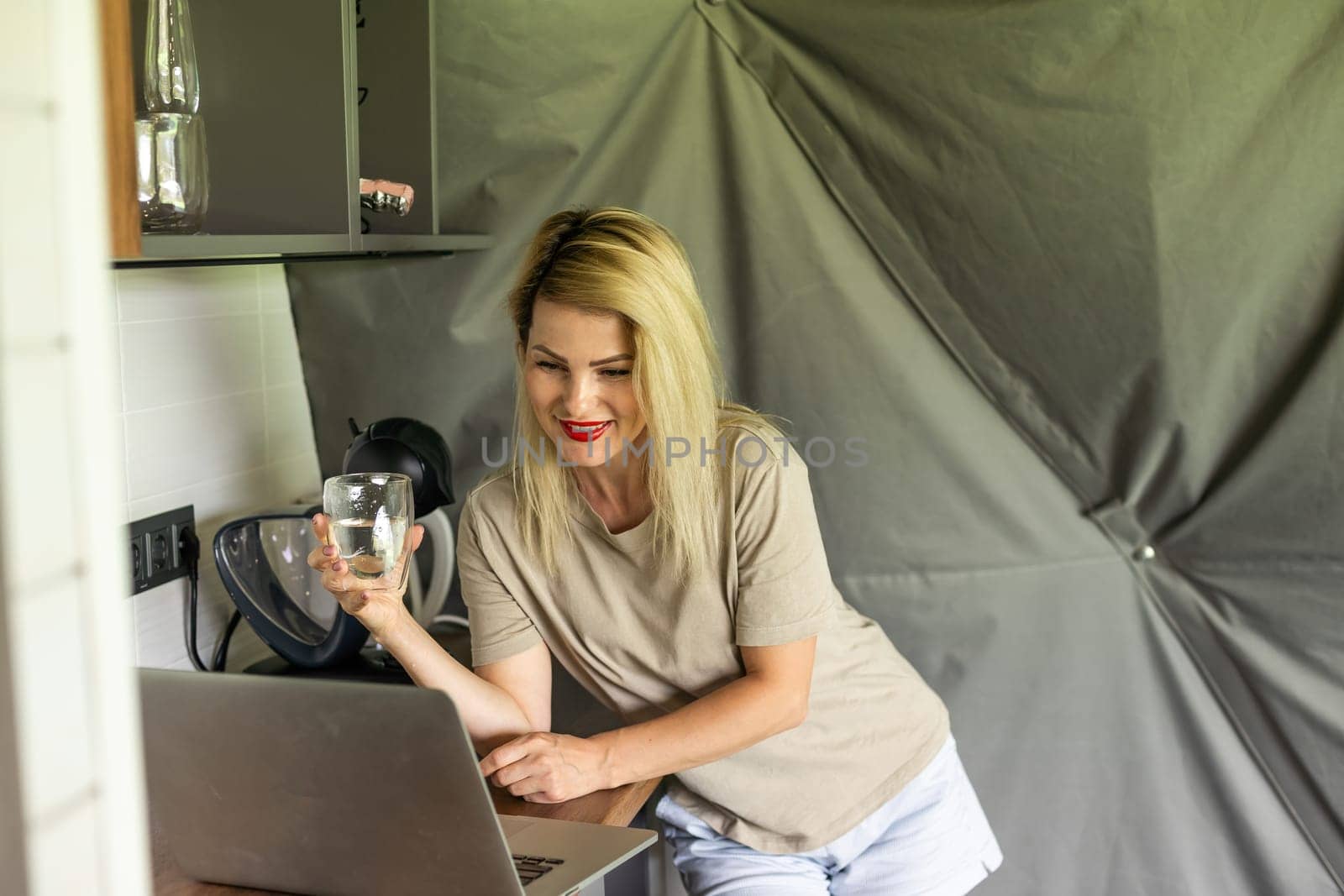 Young blonde woman with long hair using laptop in a kitchen by Andelov13